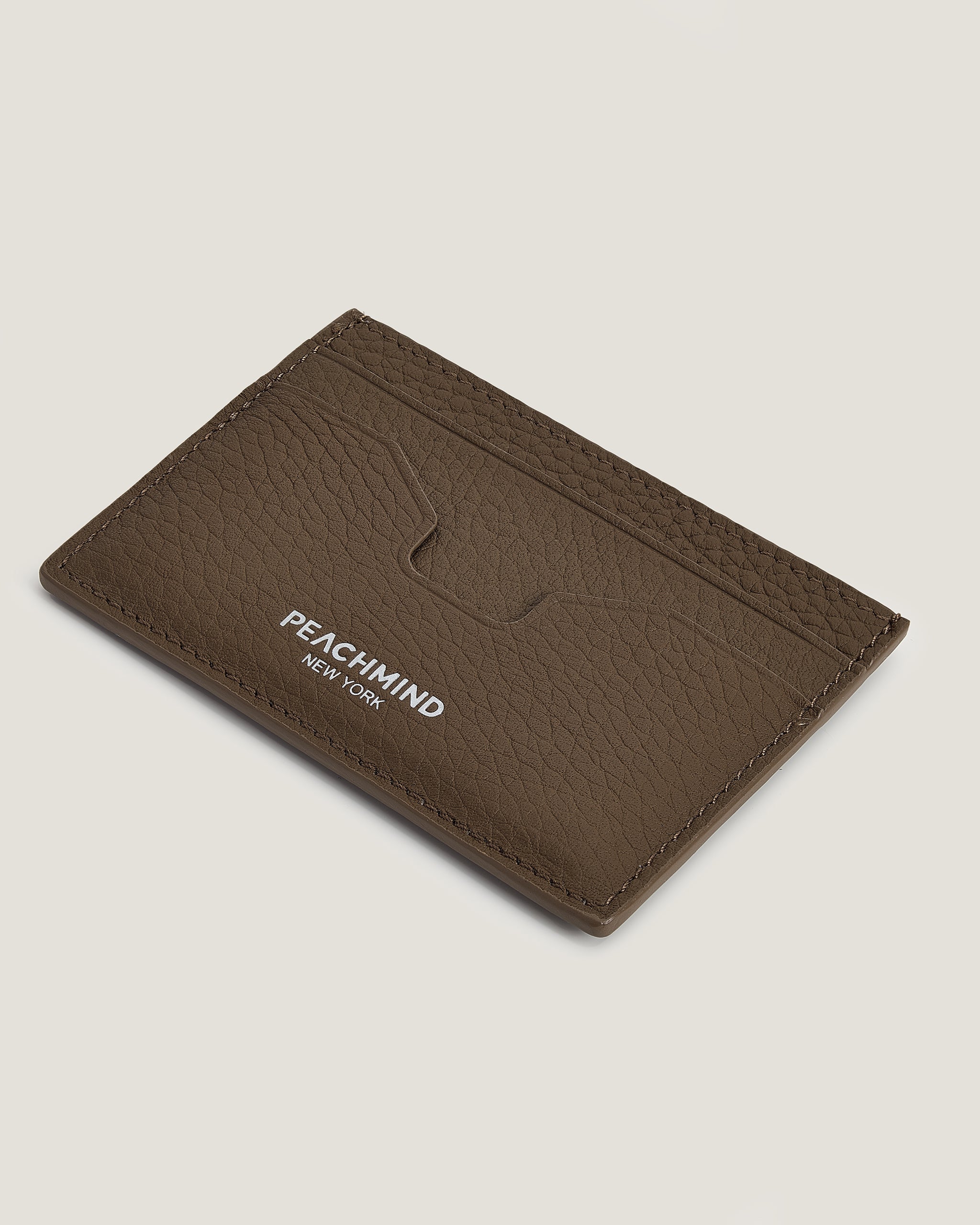 Brown leather cardholder with 'Peachmind New York' branding on a beige background
