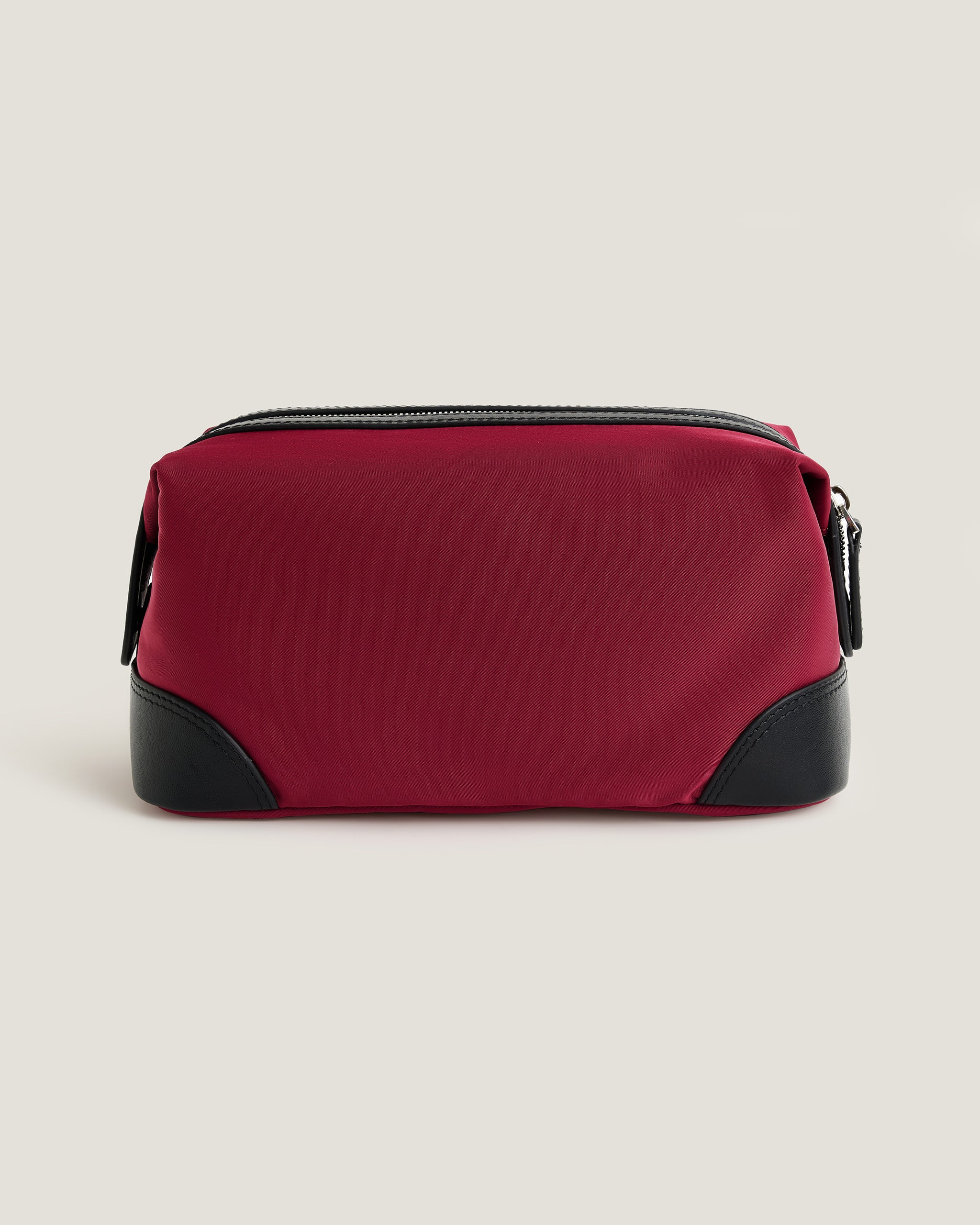 Red toiletry bag with black accents on a beige background