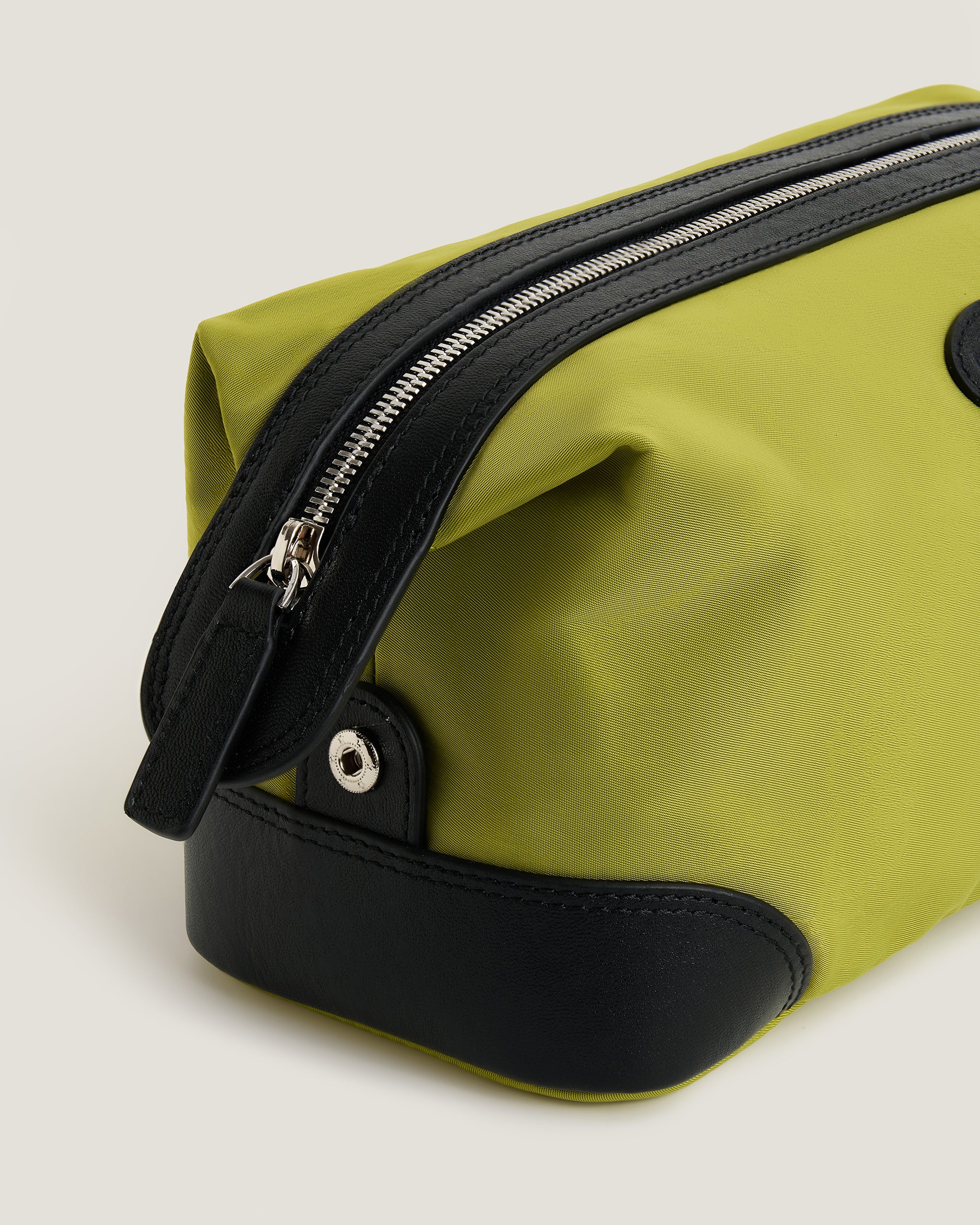 Green toiletry bag with black accents on a light gray background