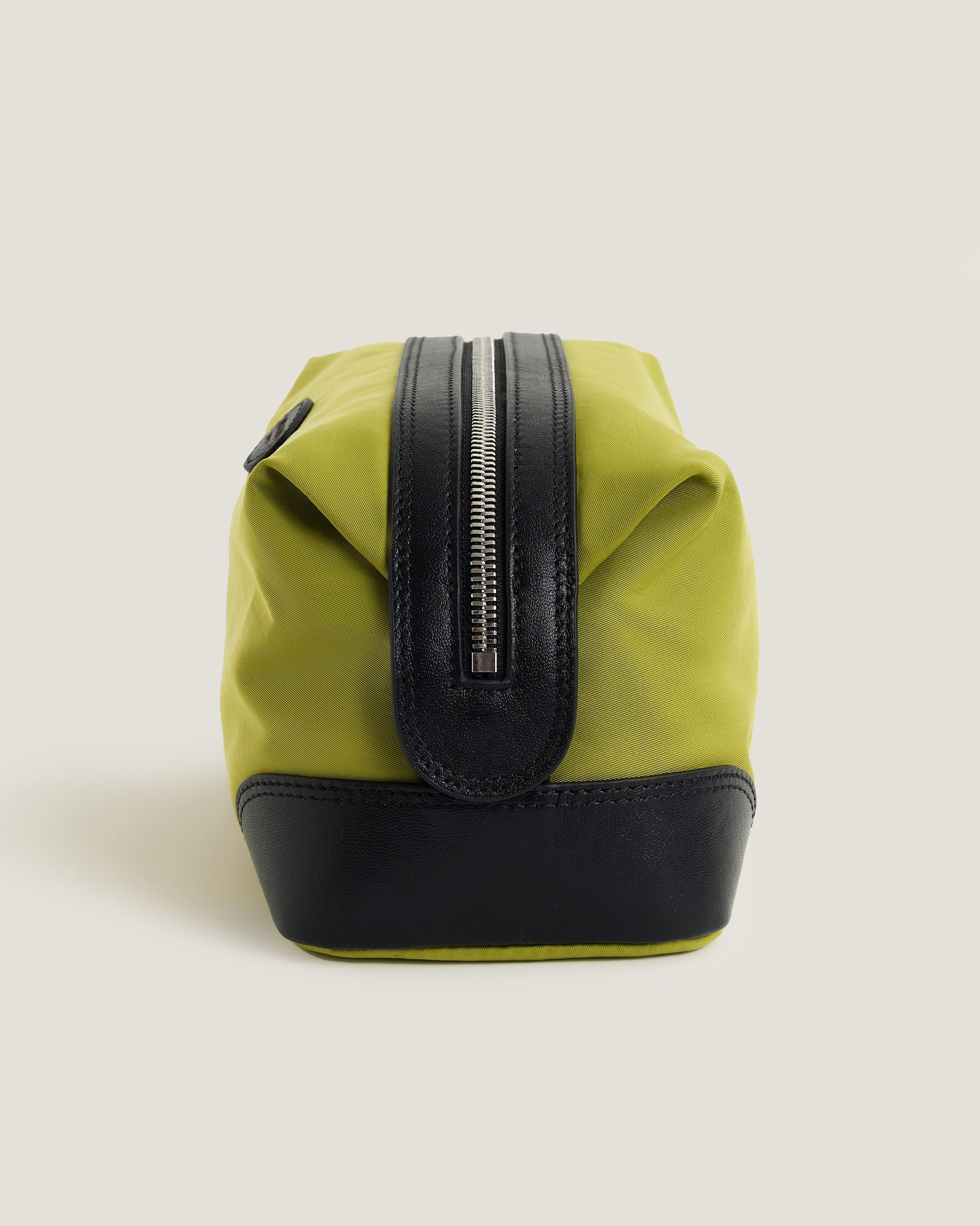 Green and black bag with a zipper on a light beige background