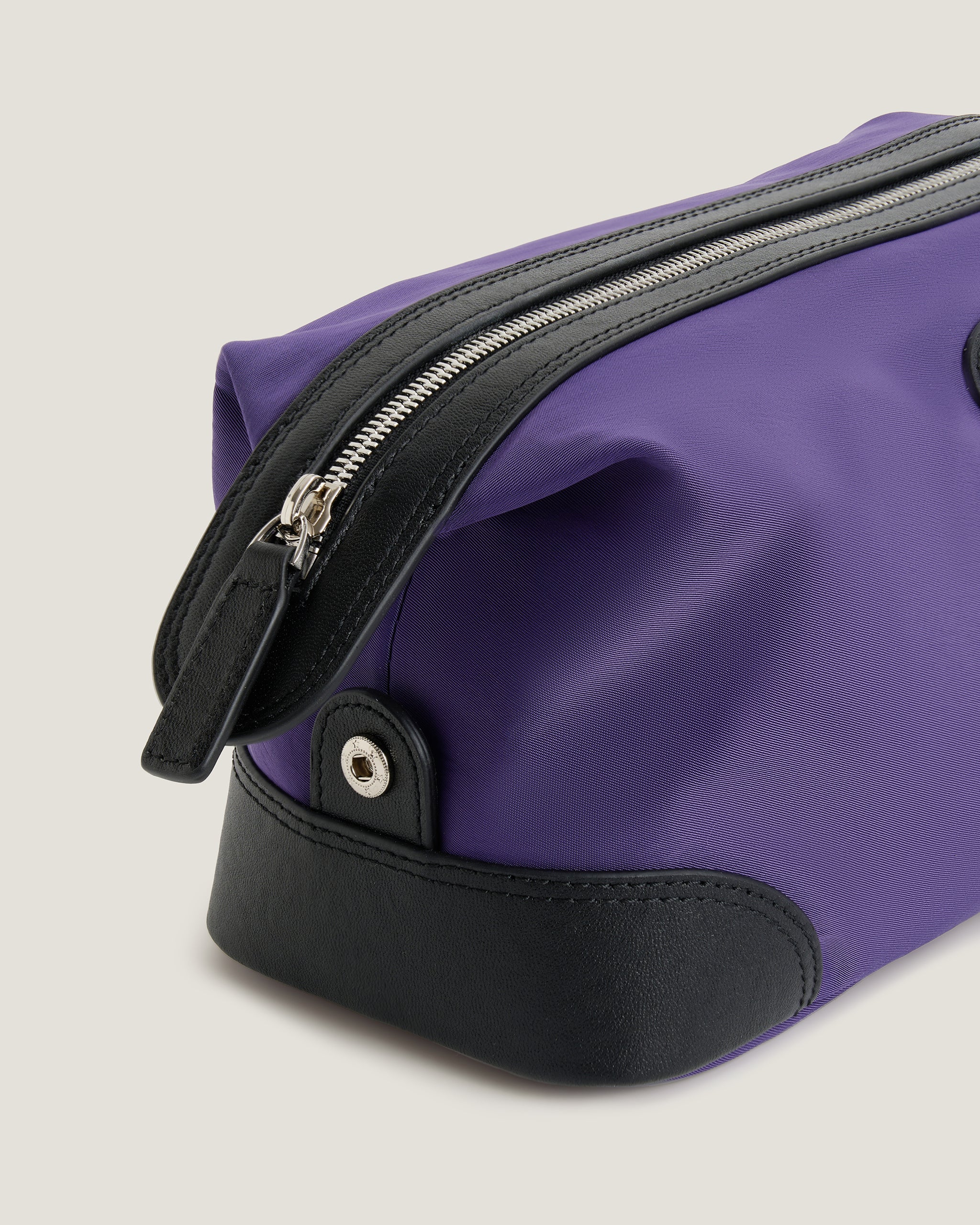 Green bag with black accents and a zipper on a light gray background