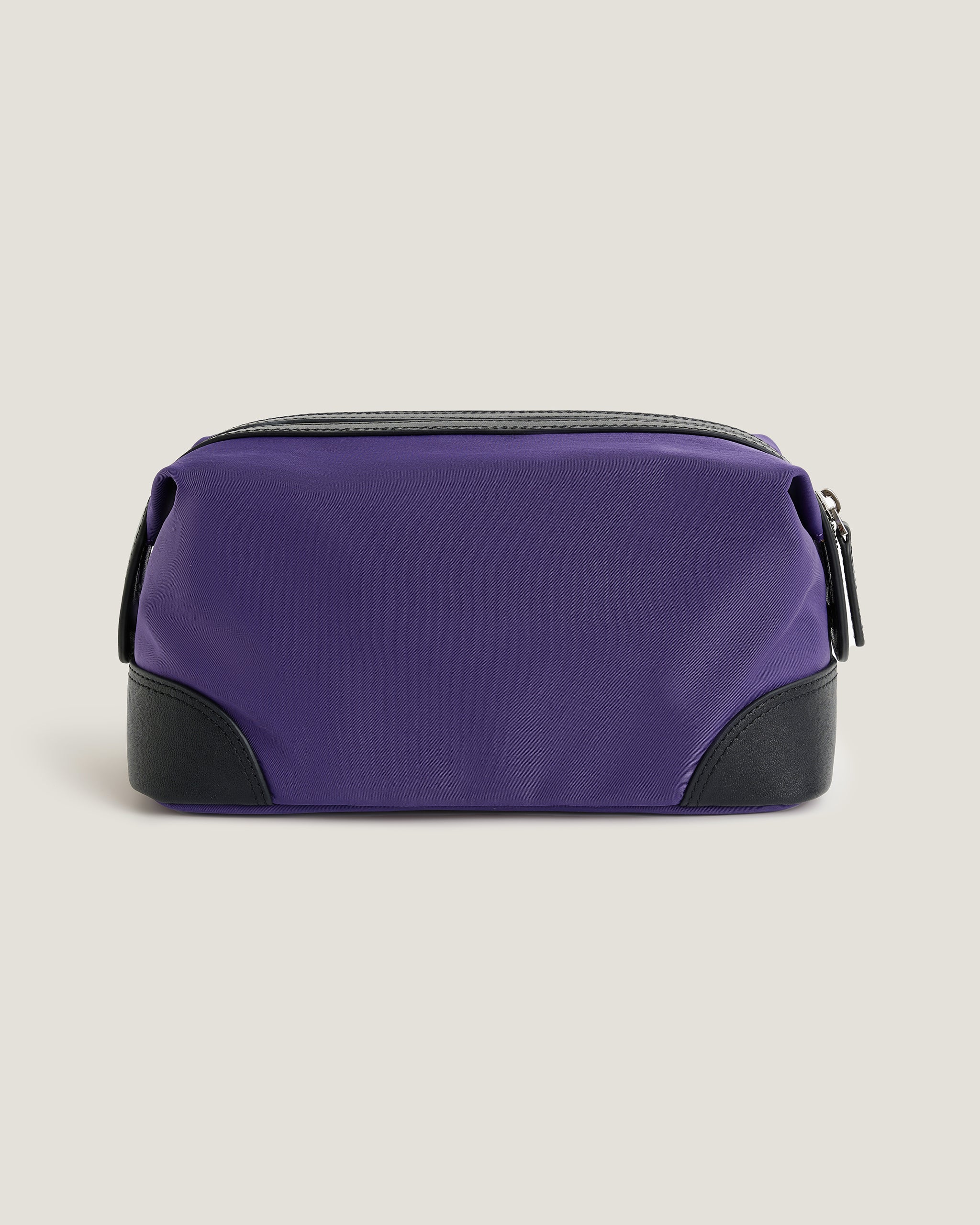 Purple toiletry bag with black accents on a beige background