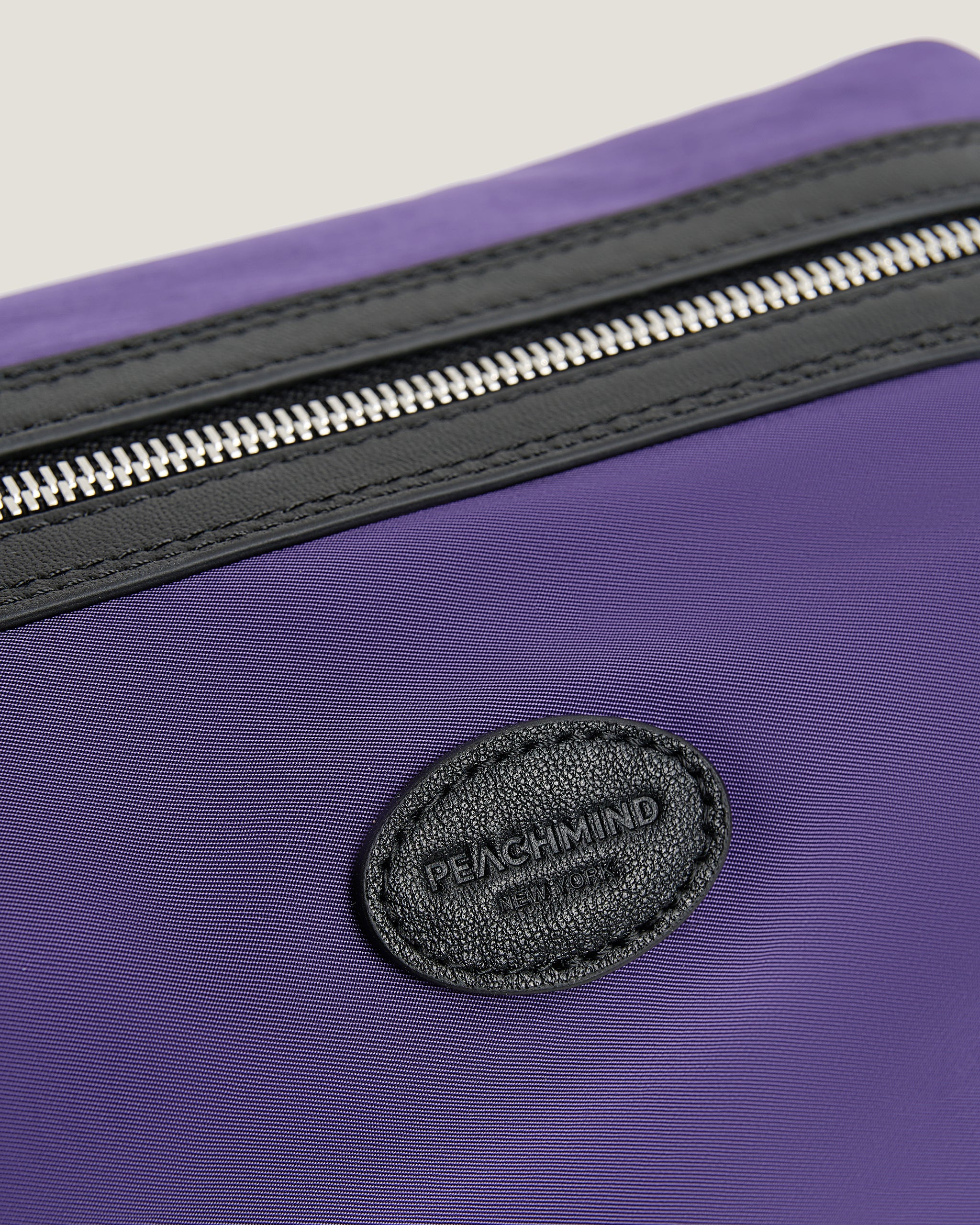 Green bag with a black zipper and visible brand logo on a light gray background