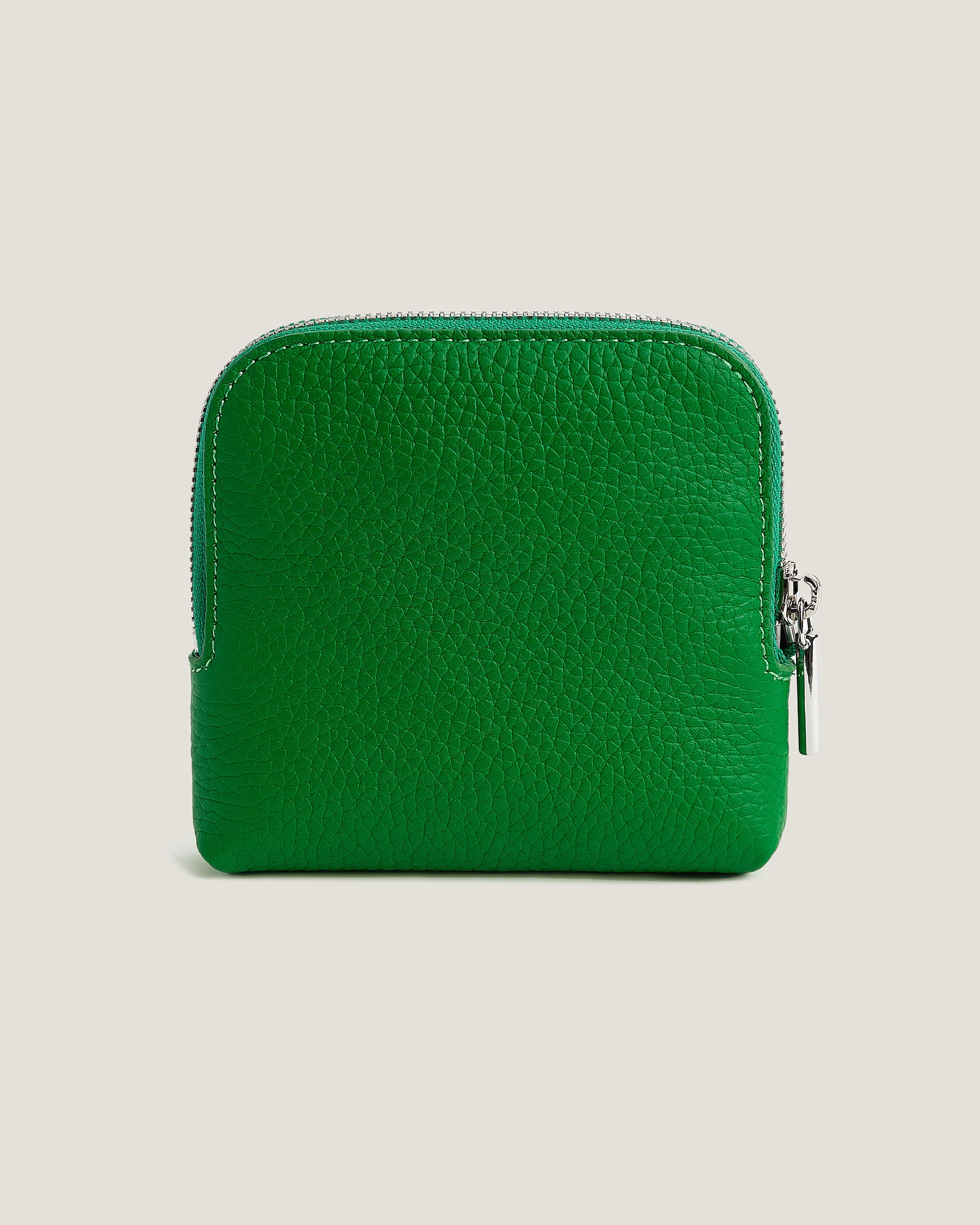 Green leather wallet with a zipper on a beige background