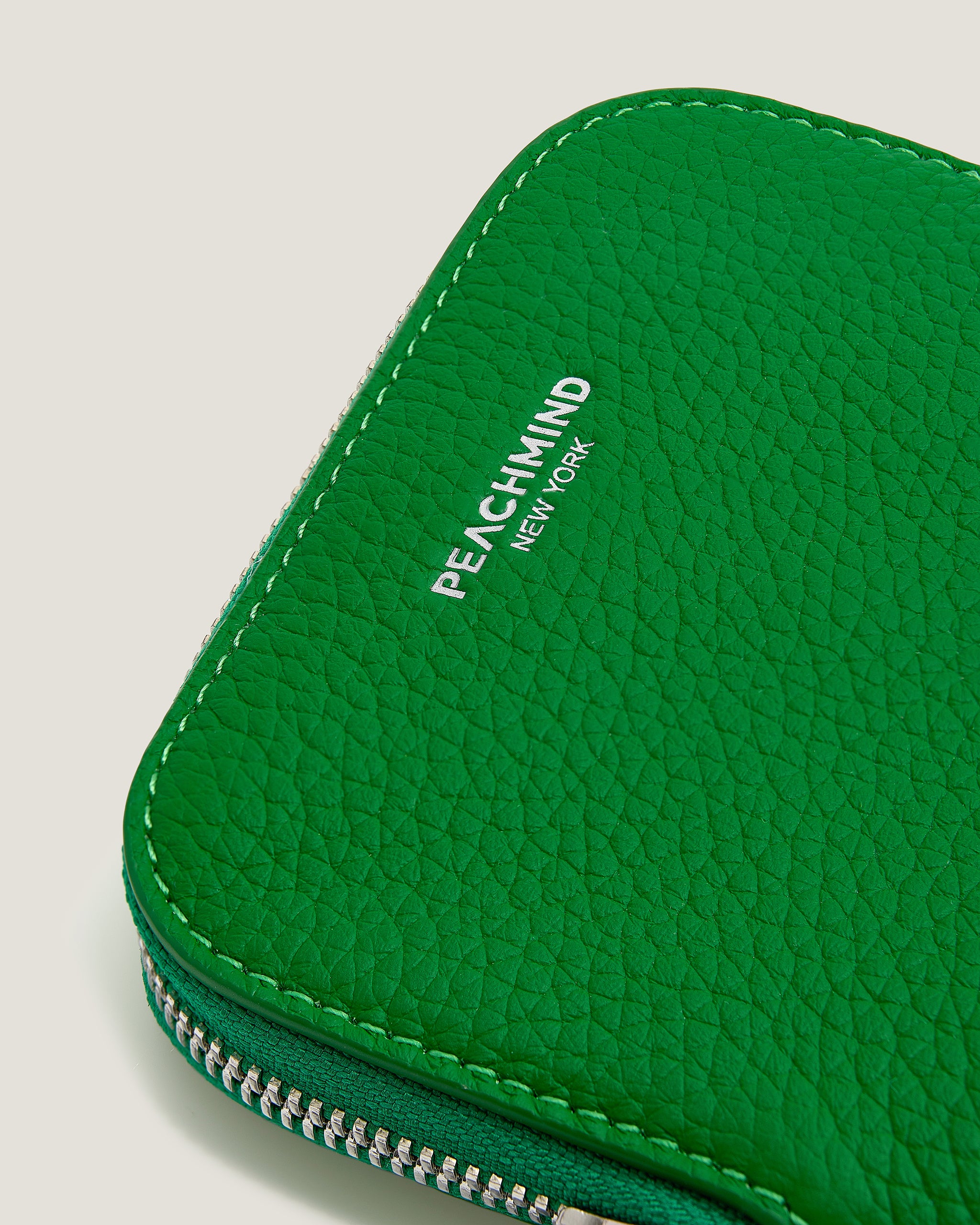 Green textured pouch with 'Peachmind New York' branding on a light gray background