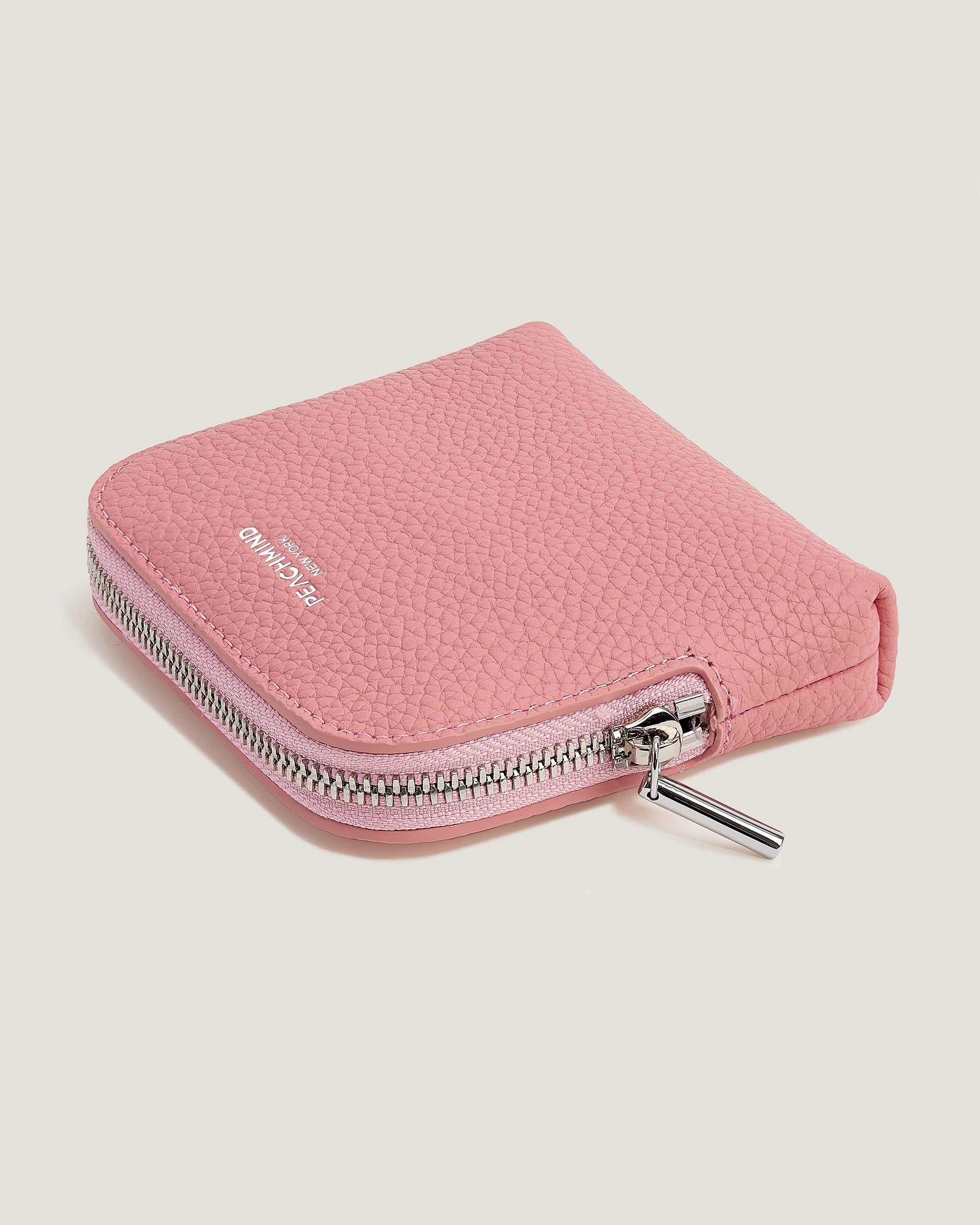 Pink zip-up pouch with a brand logo on a light beige background