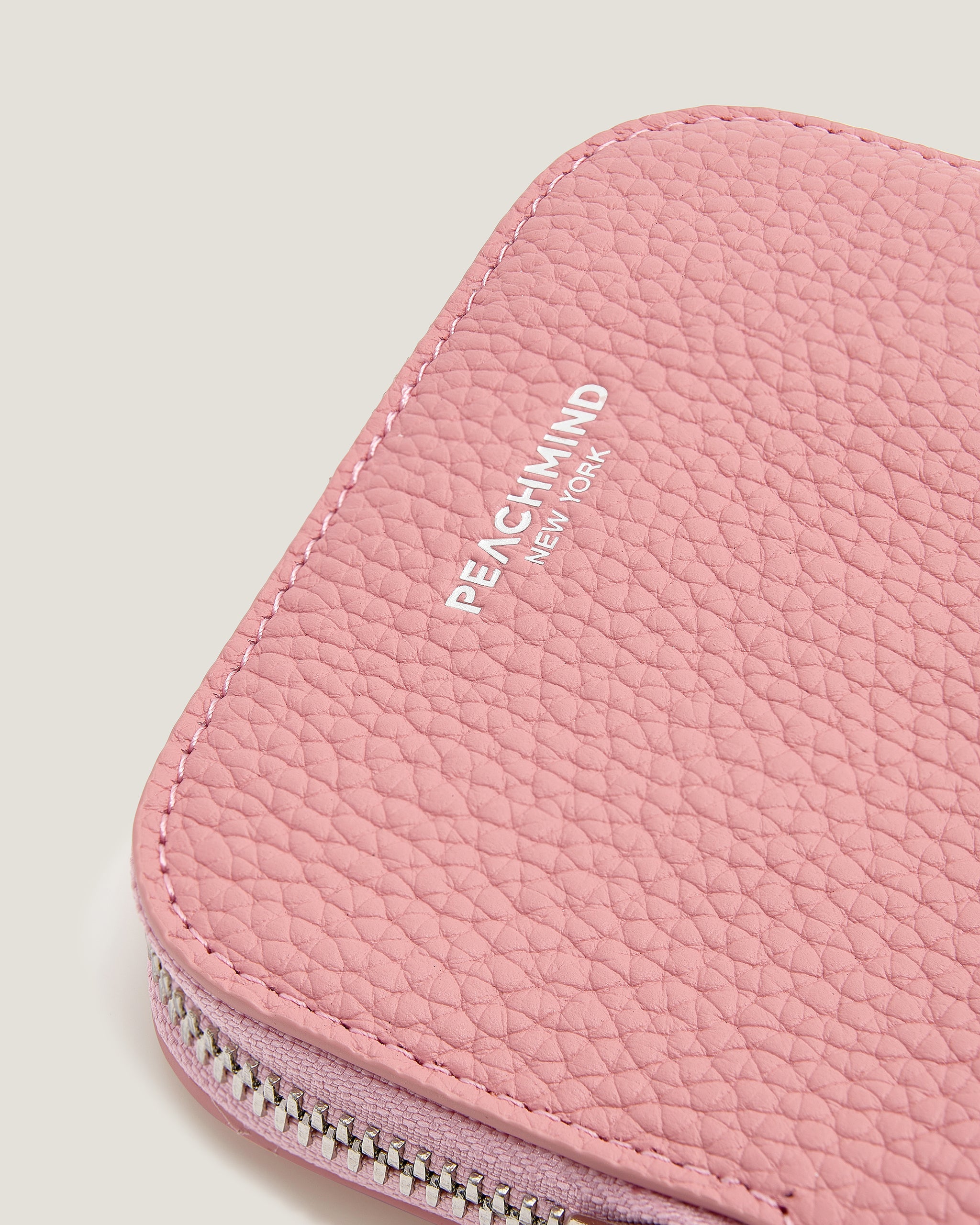 Pink textured pouch with 'Peachmind New York' branding on a light gray background