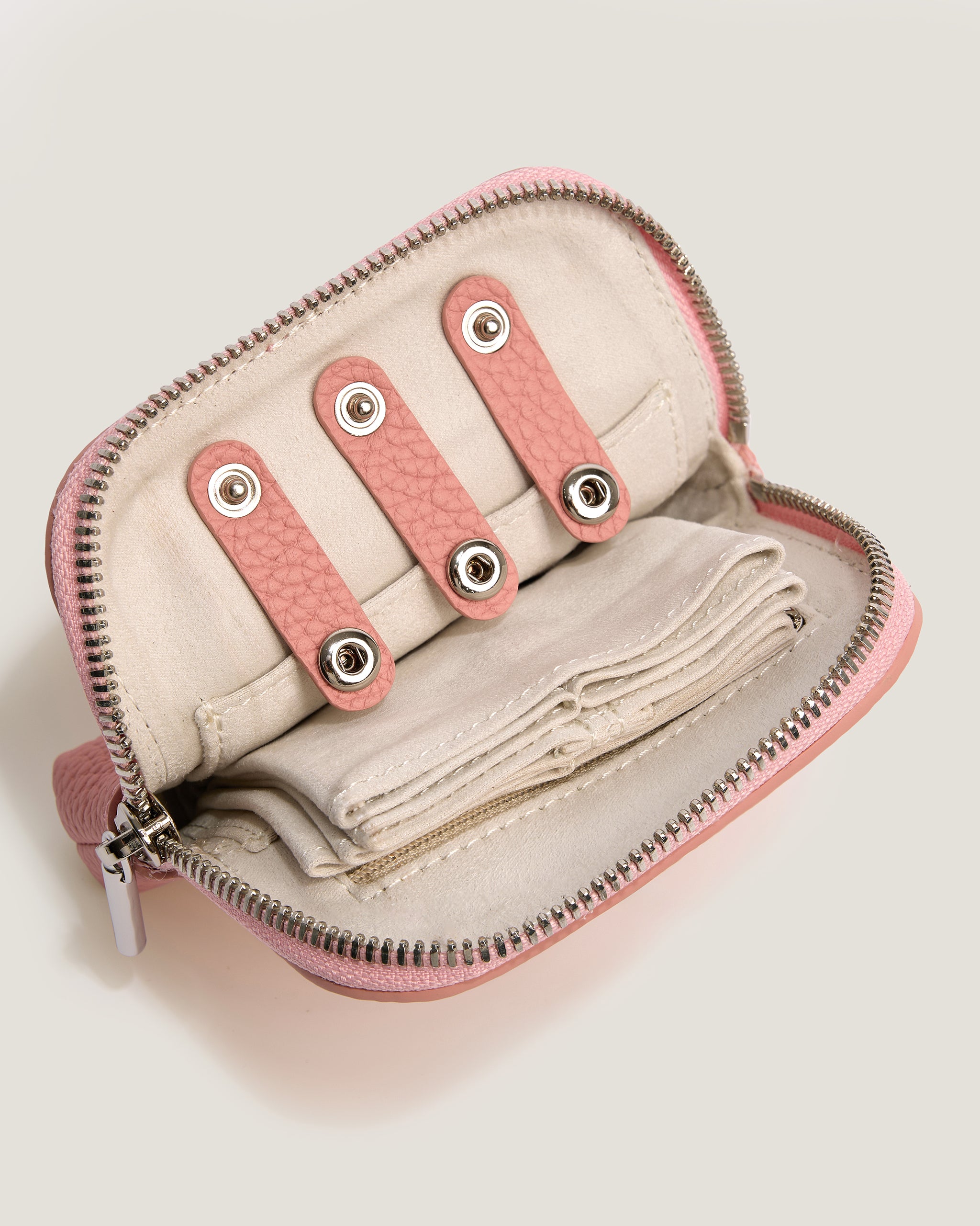 Small beige pouch with pink zippers and decorative elements on a light gray background