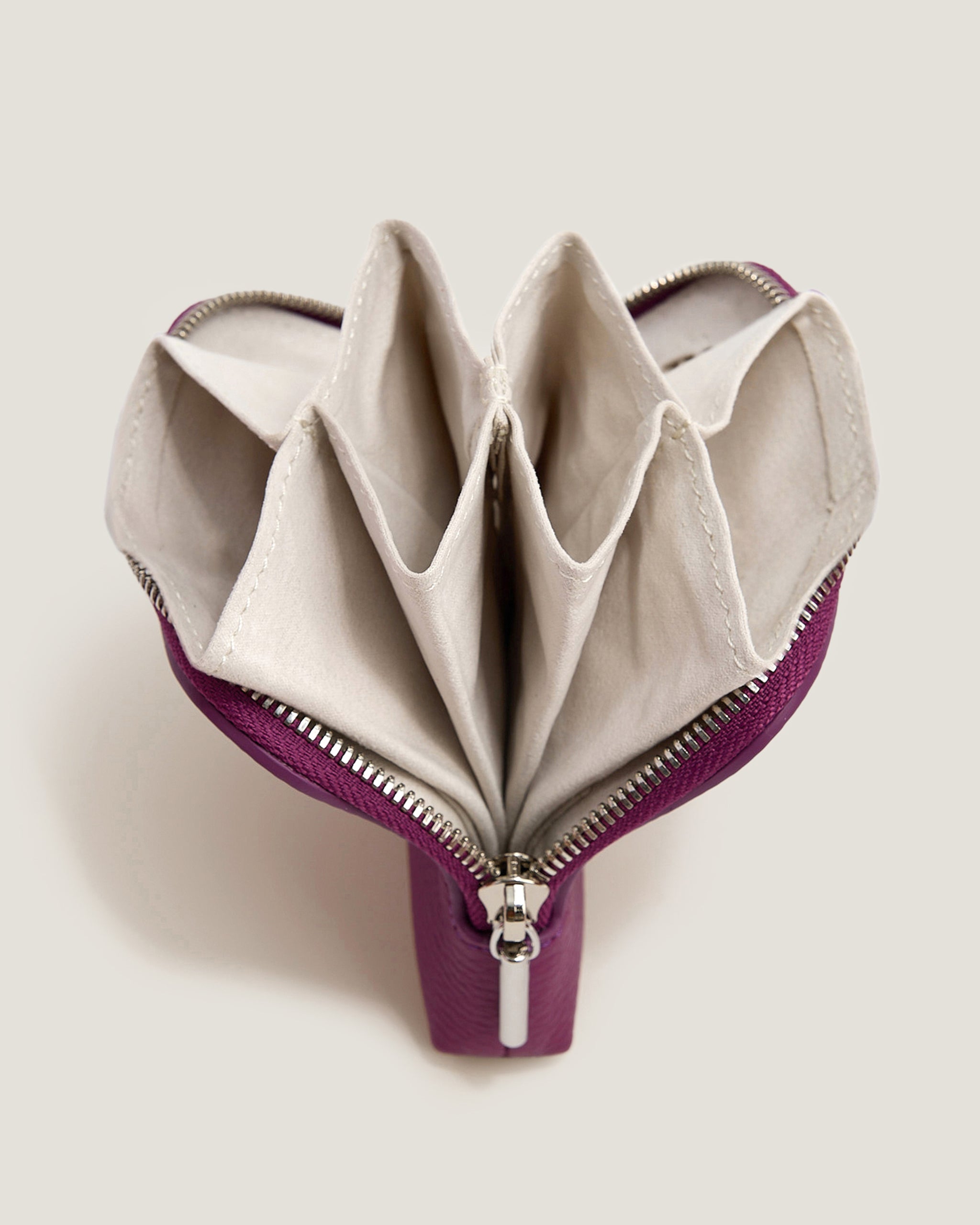 Foldable beige wallet with purple zipper on a light gray background
