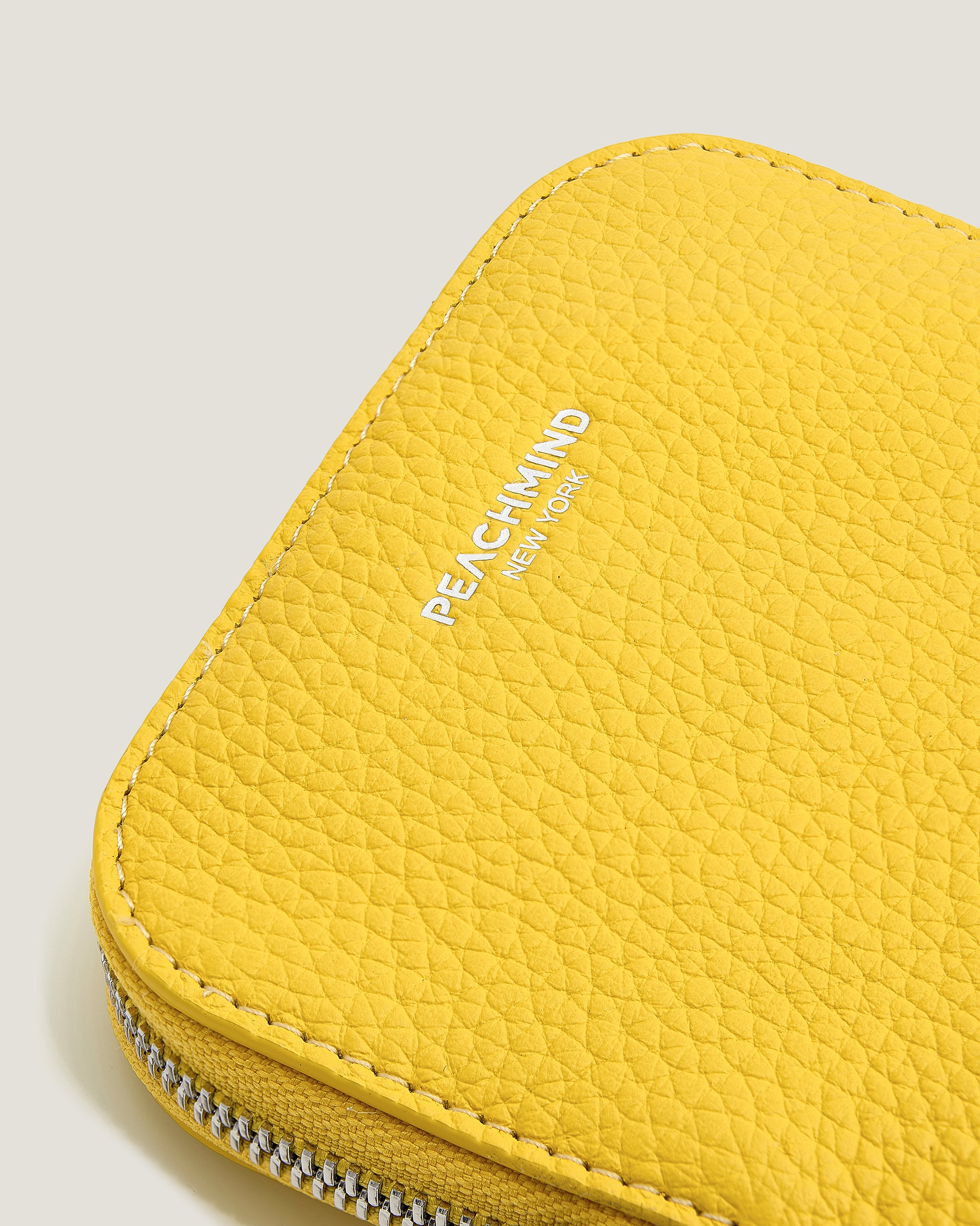Yellow zippered pouch with 'Peachand' branding on a light gray background