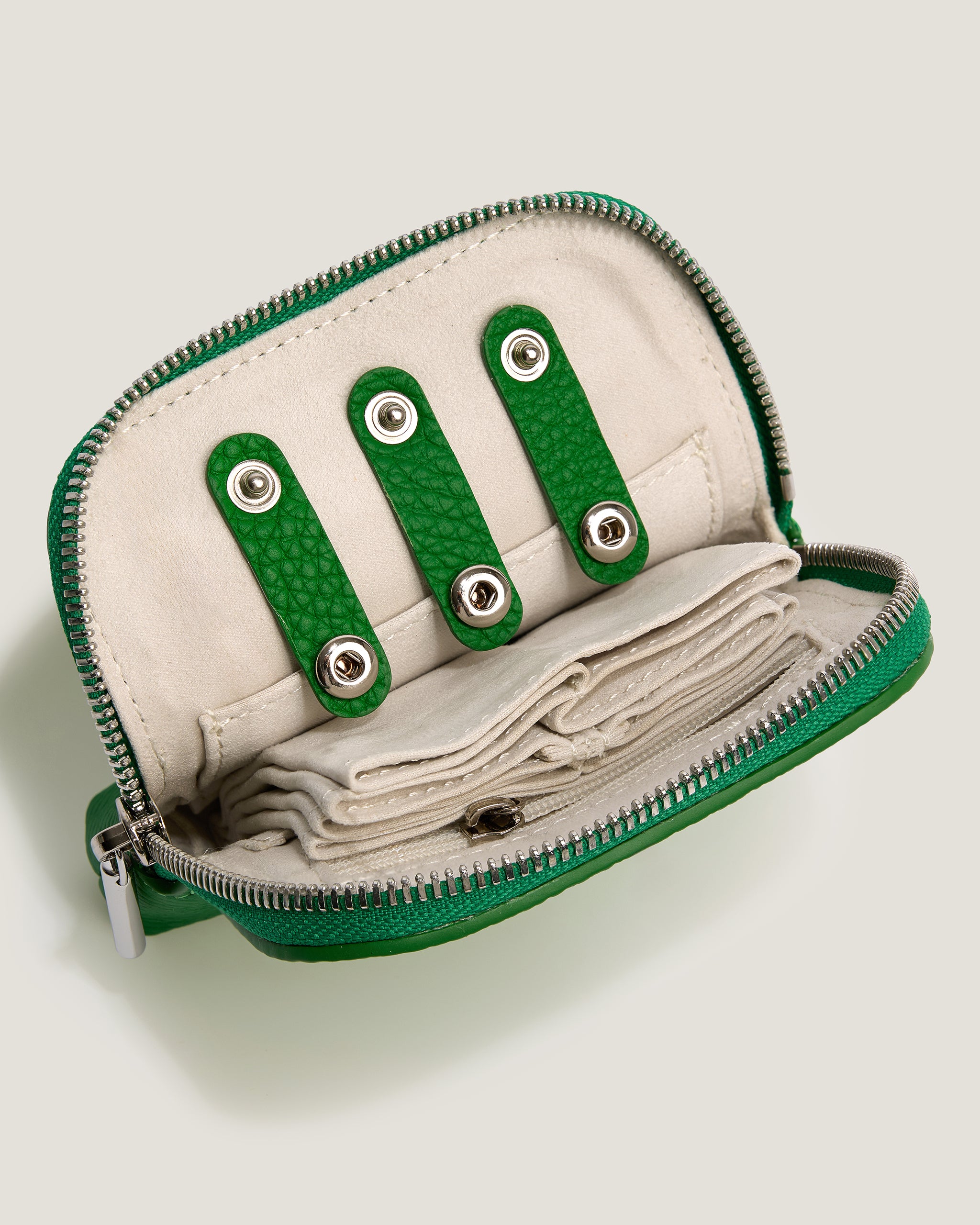 Green and beige zippered pouch with decorative elements on a light gray background