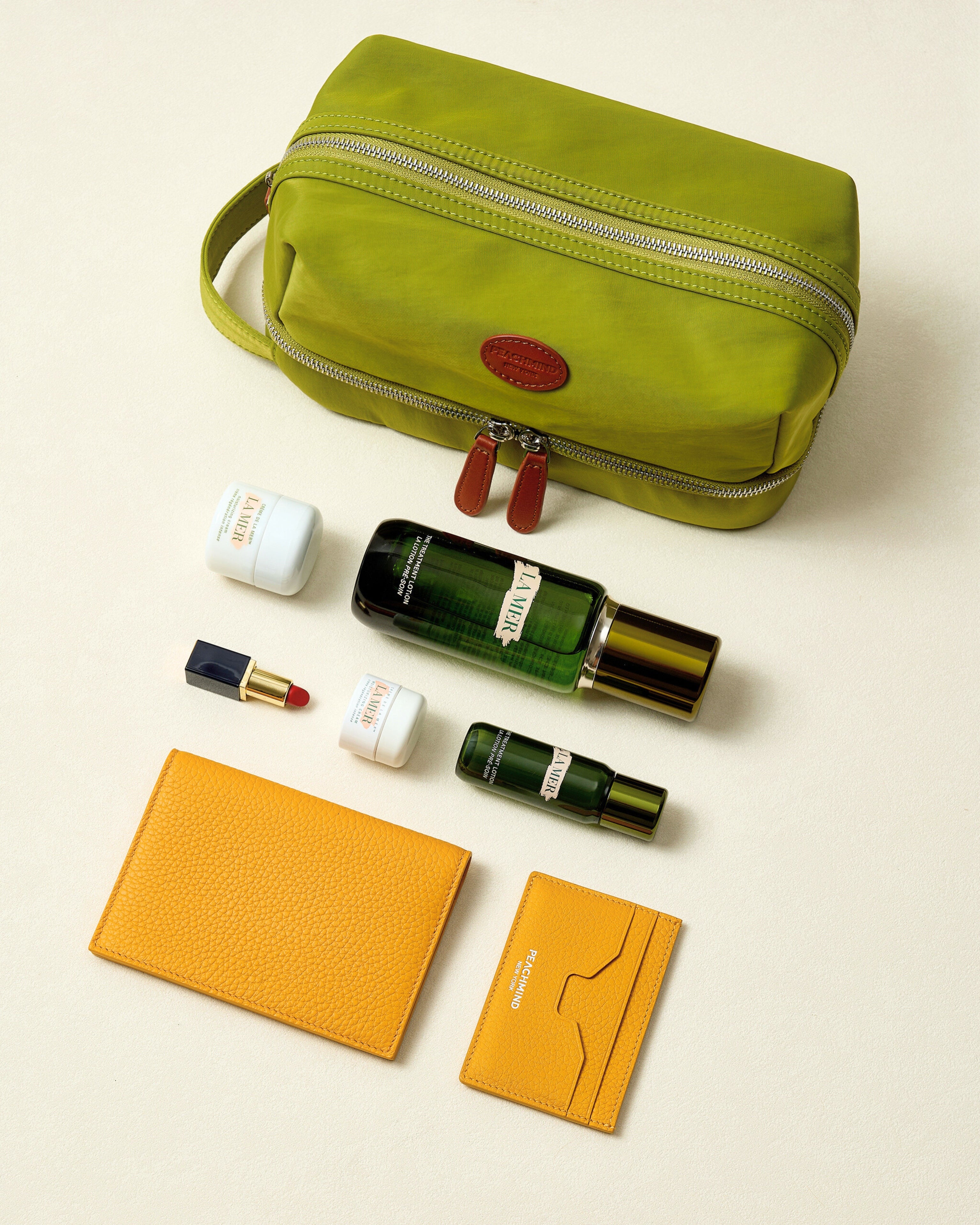 Green toiletry bag with cosmetic items on a beige background