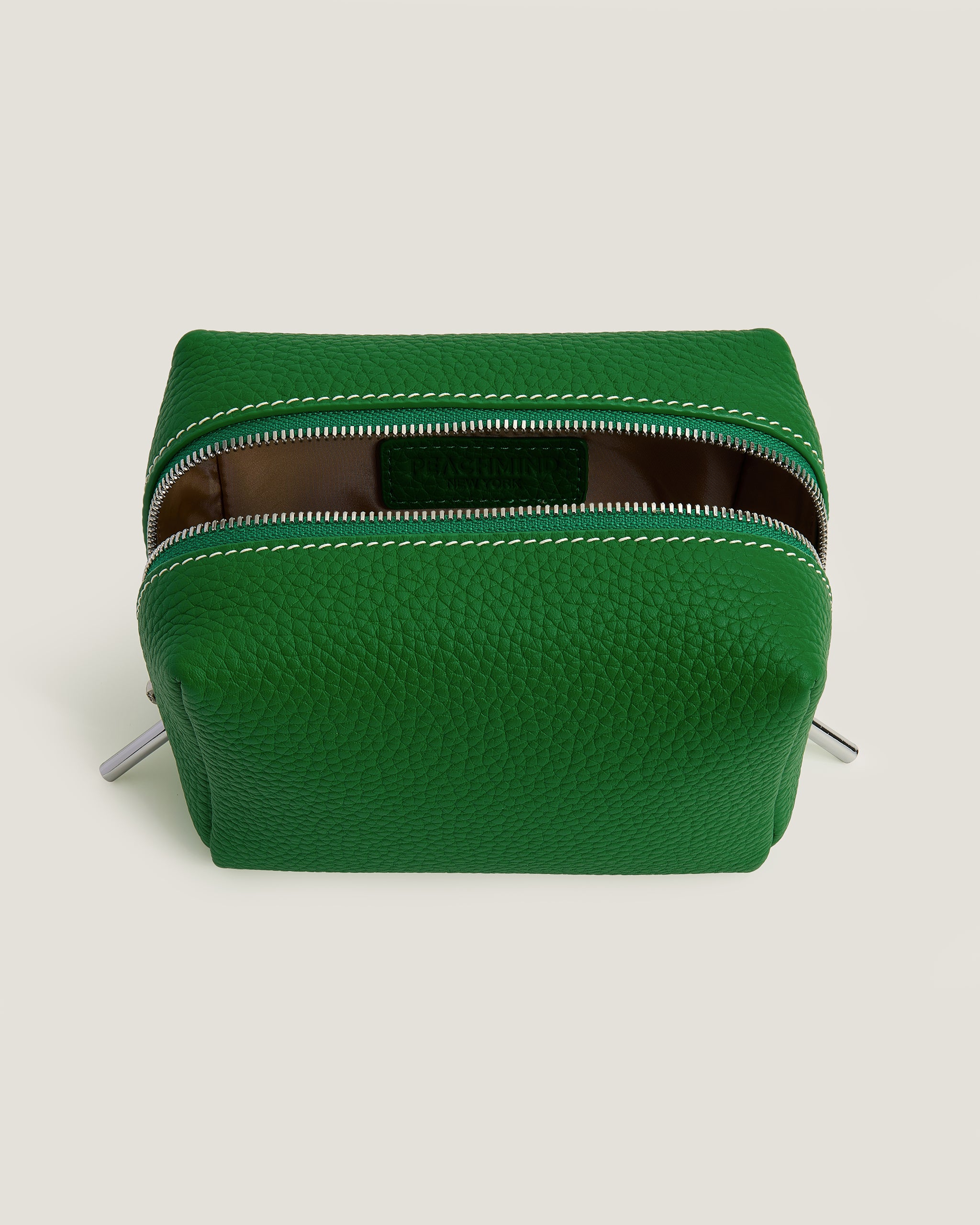 Green leather pouch with a zipper on a light beige background