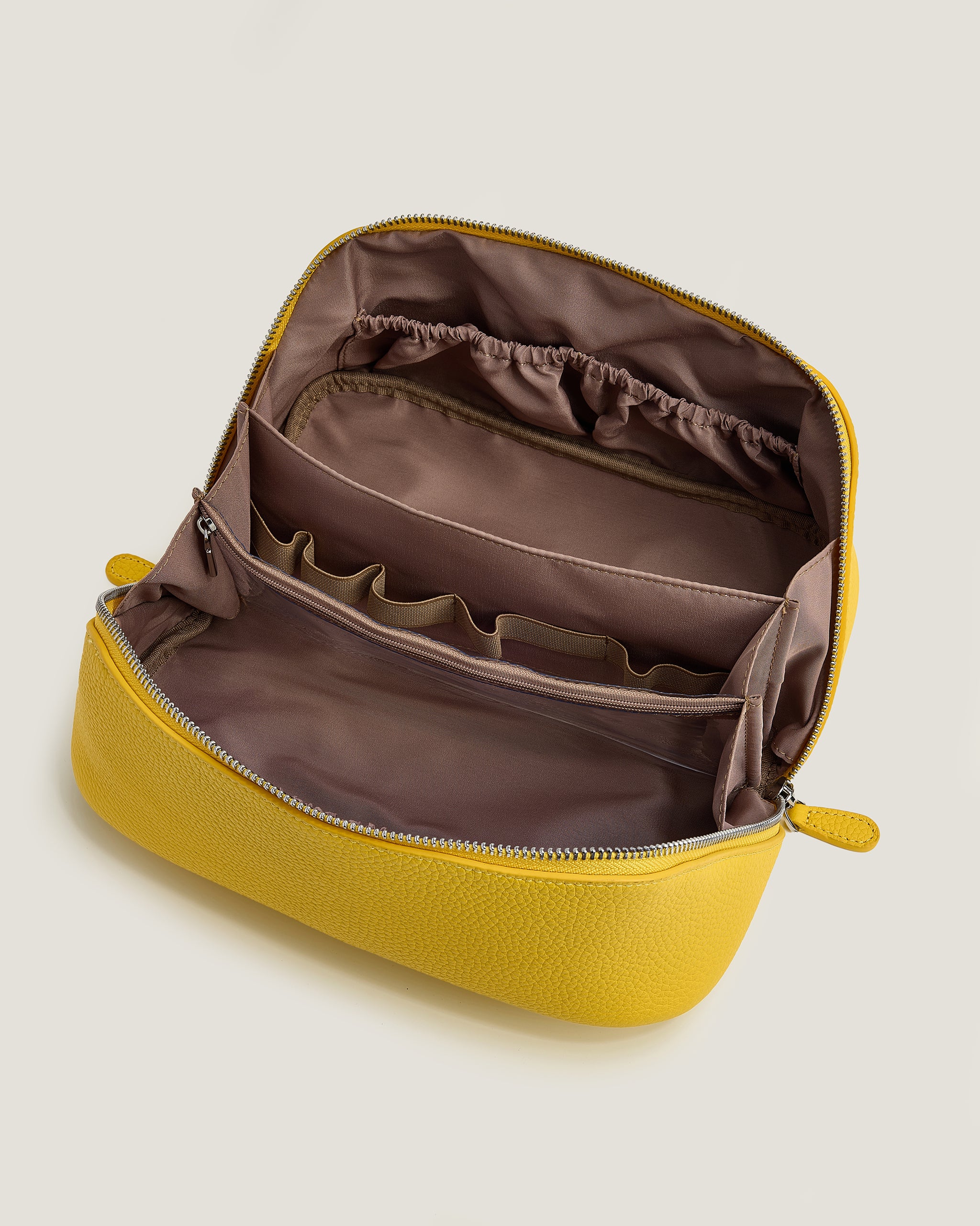 Yellow makeup bag with brown interior on a light beige background