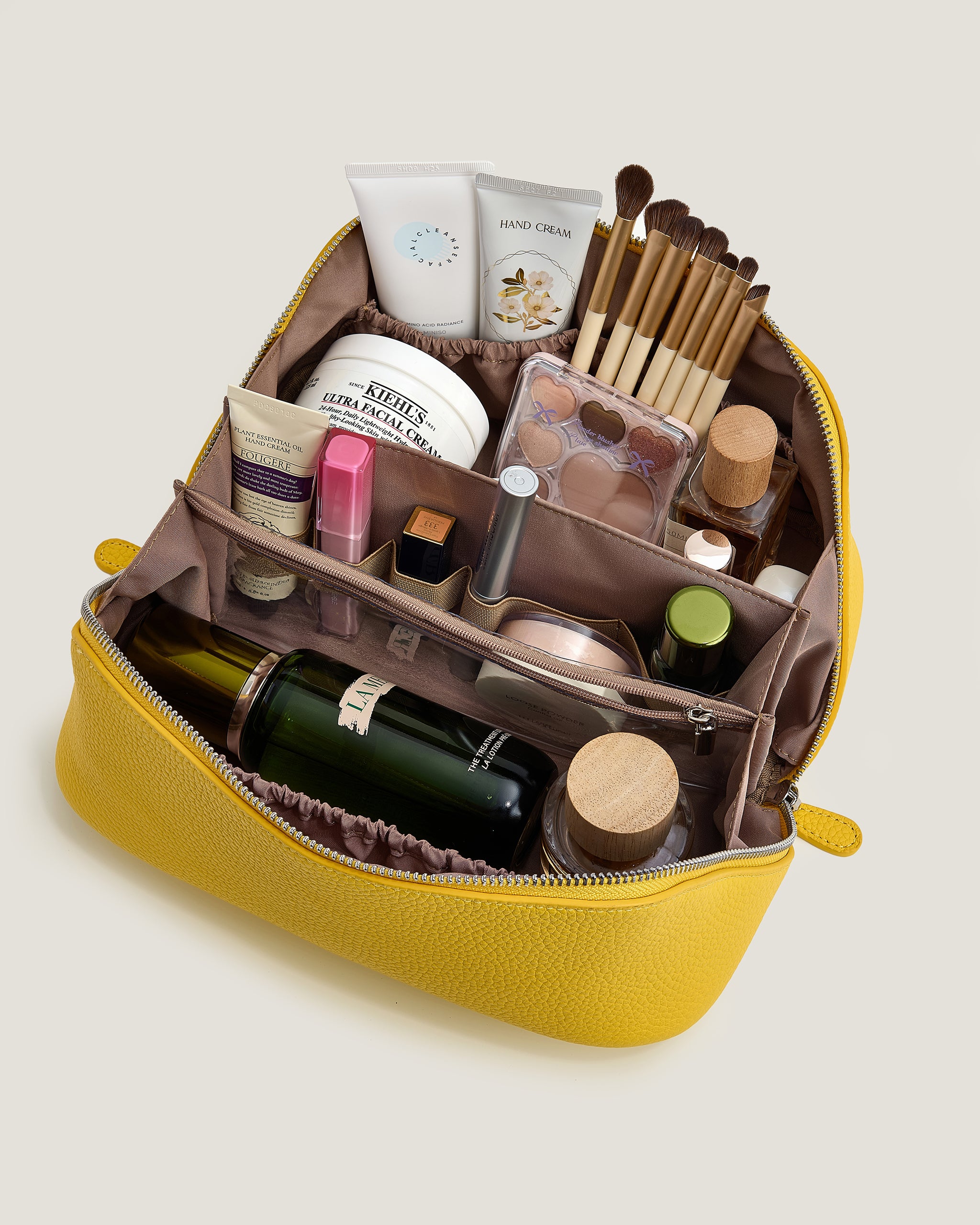 Yellow makeup bag with various cosmetic items on a light beige background