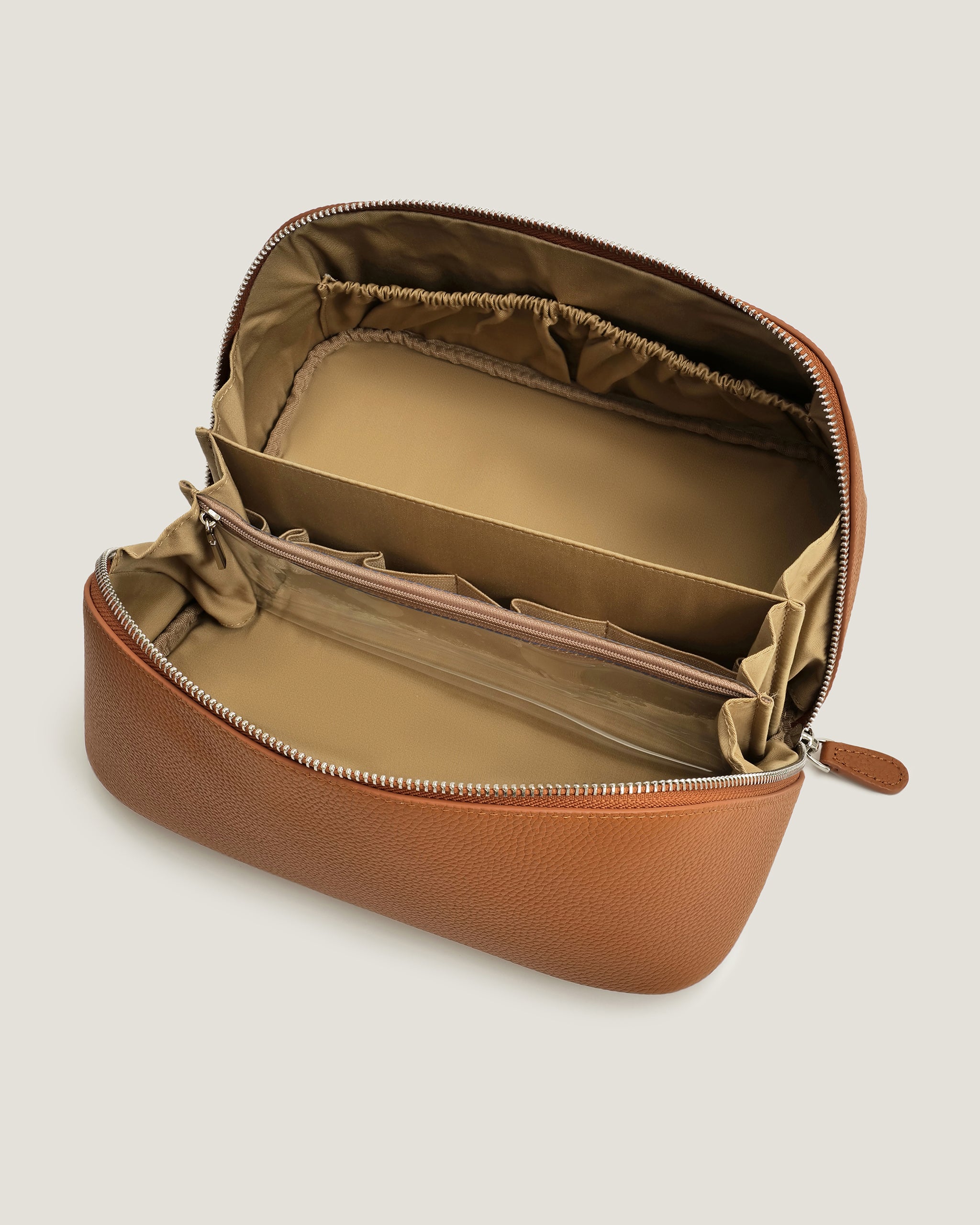 Brown leather open flat makeup bag with interior compartments on a light beige background