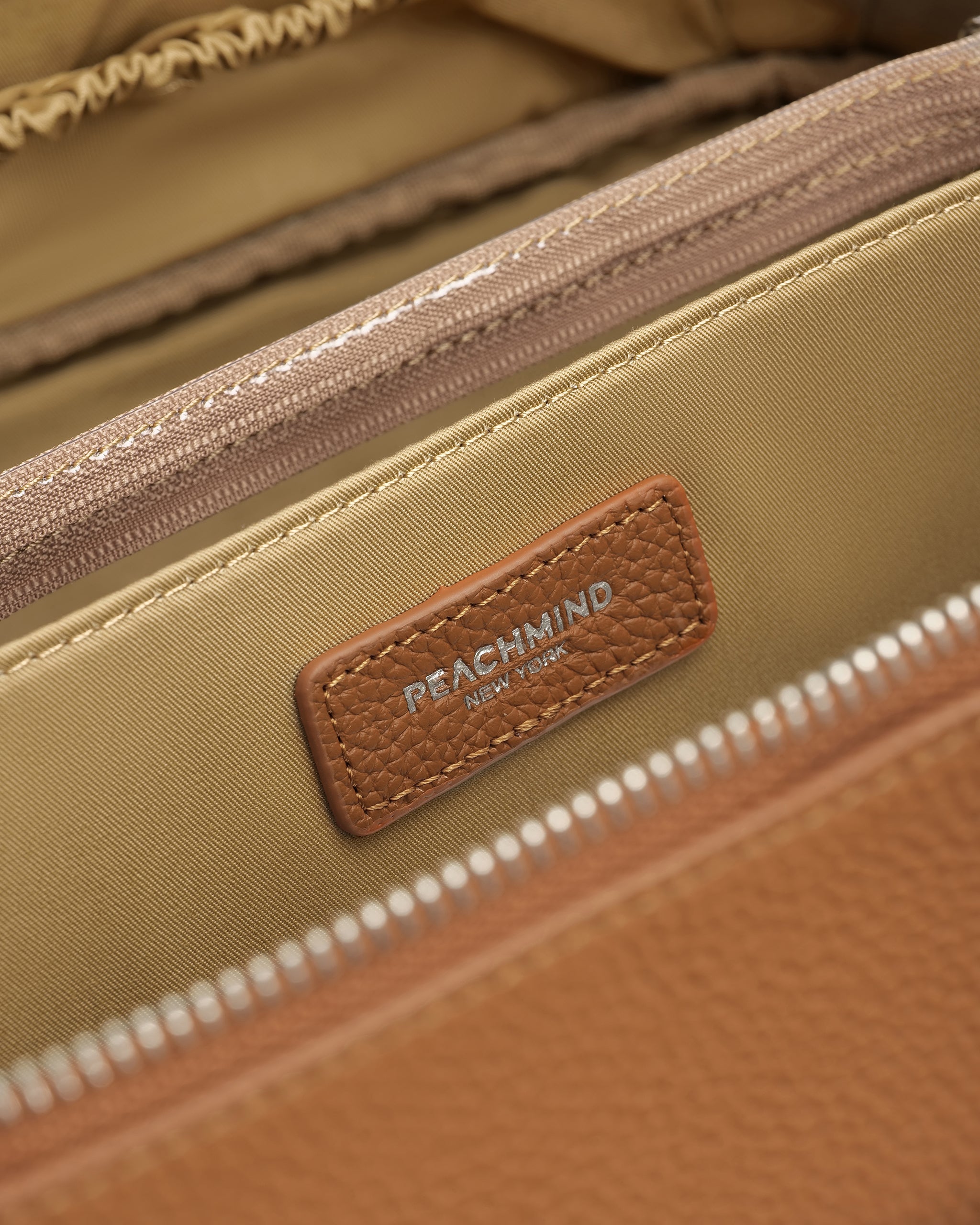 Close-up of a beige bag with a brown leather label featuring 'Peachmind' branding.