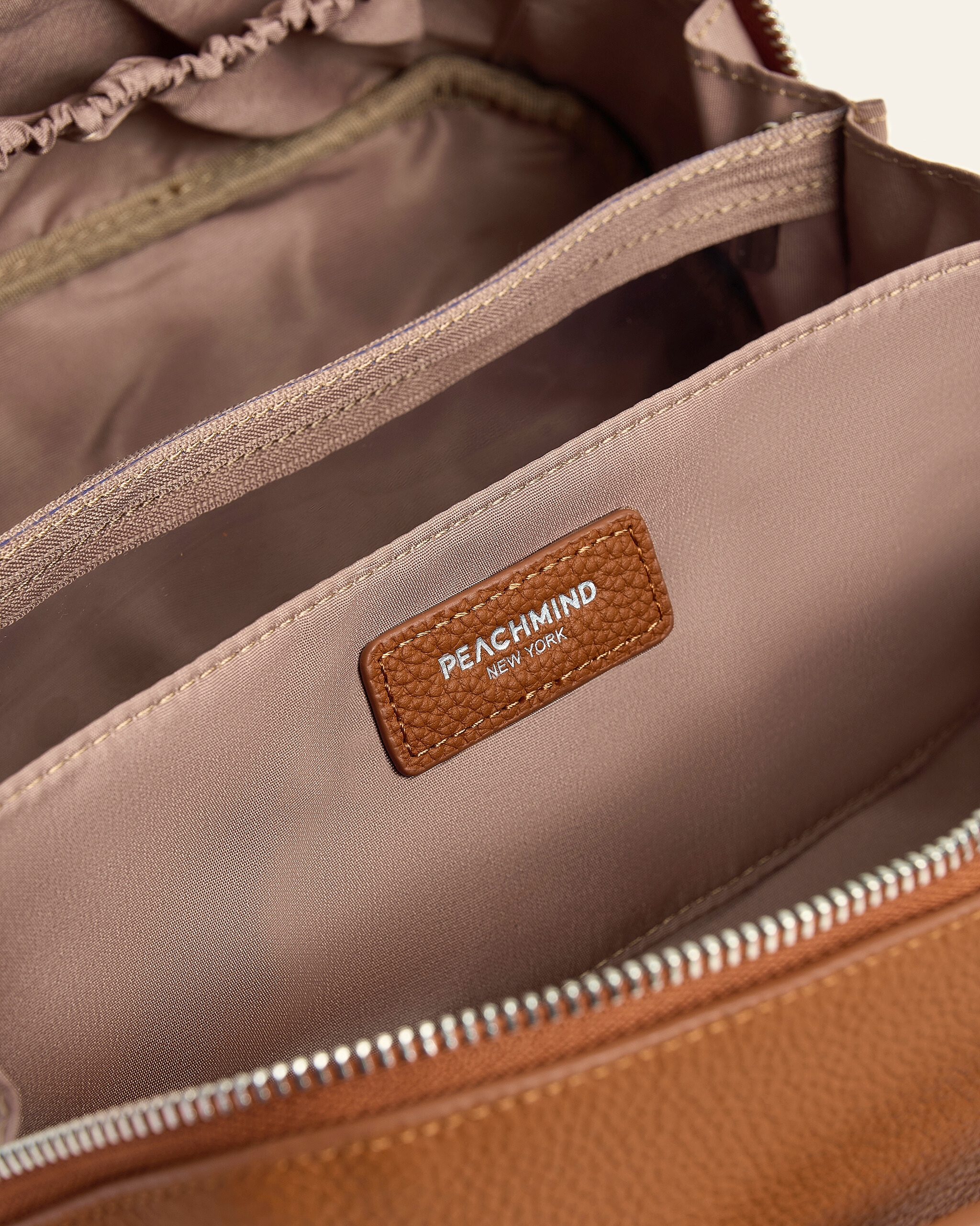 Close-up of Premium Brown Leather Makeup Bag for Women with 'Peachmind New York' label.