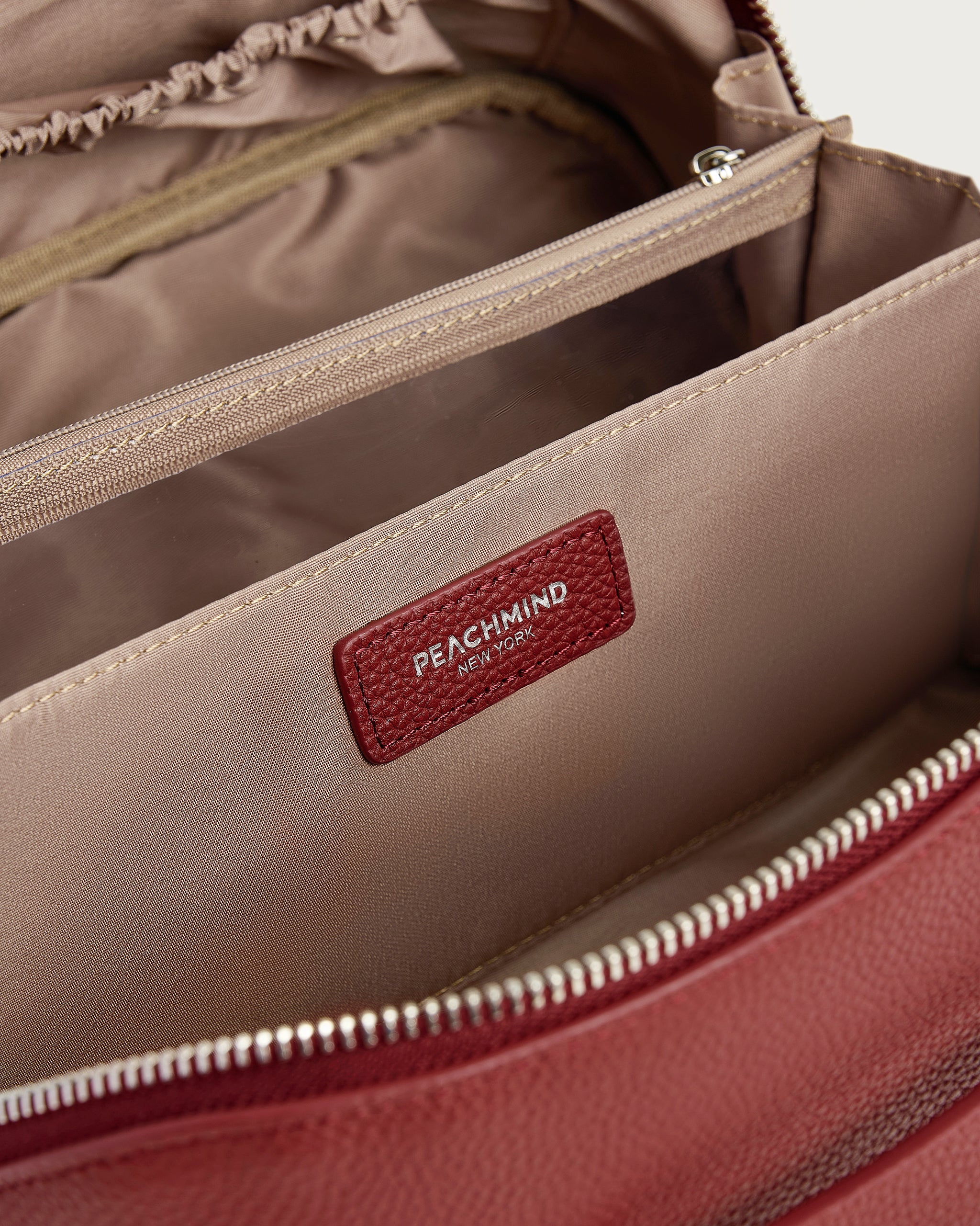Close-up of a red bag with a visible PEACHMIND NEW YORK brand label on a beige background