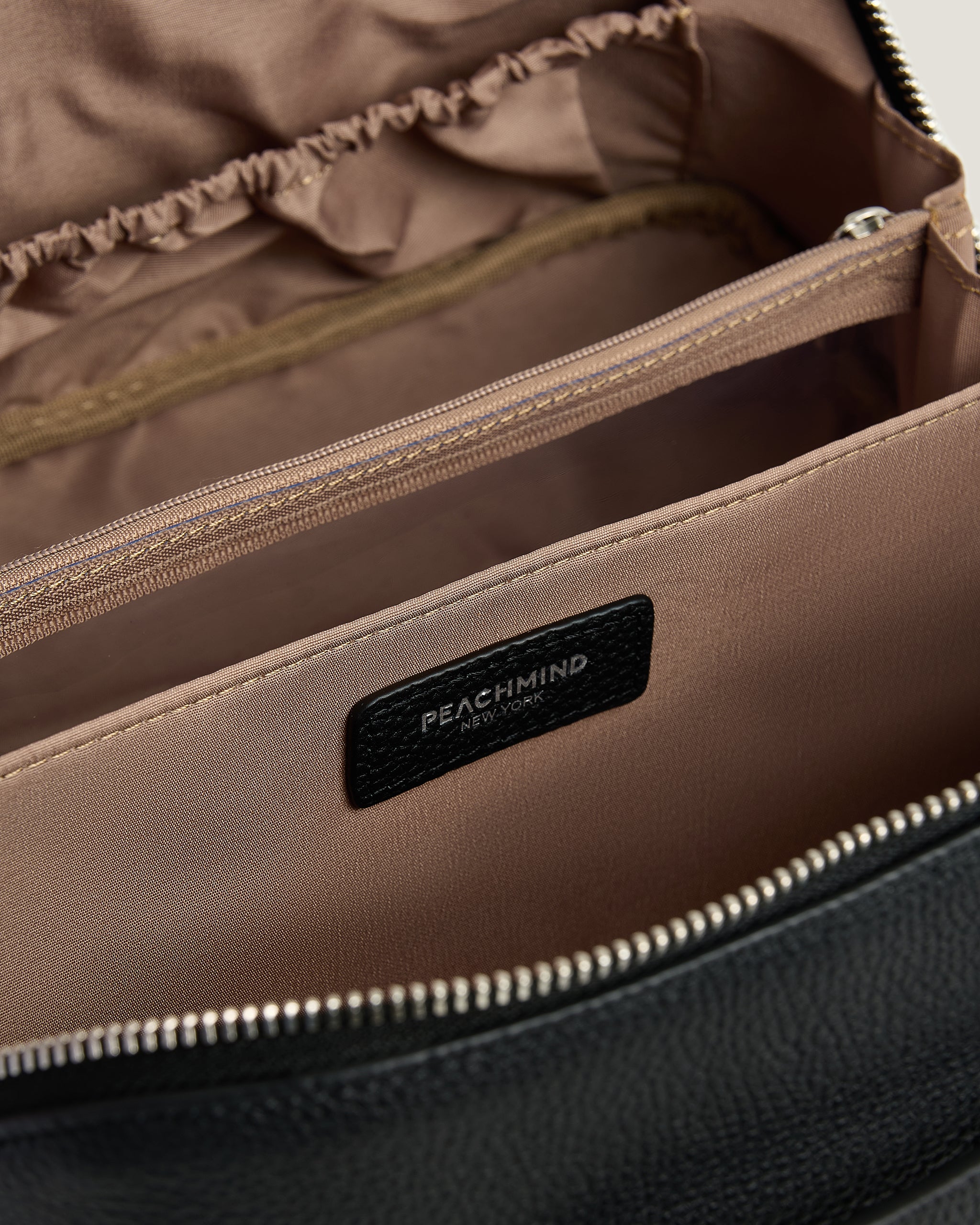 Close-up of a leather makeup bag with a visible Peachmind label.