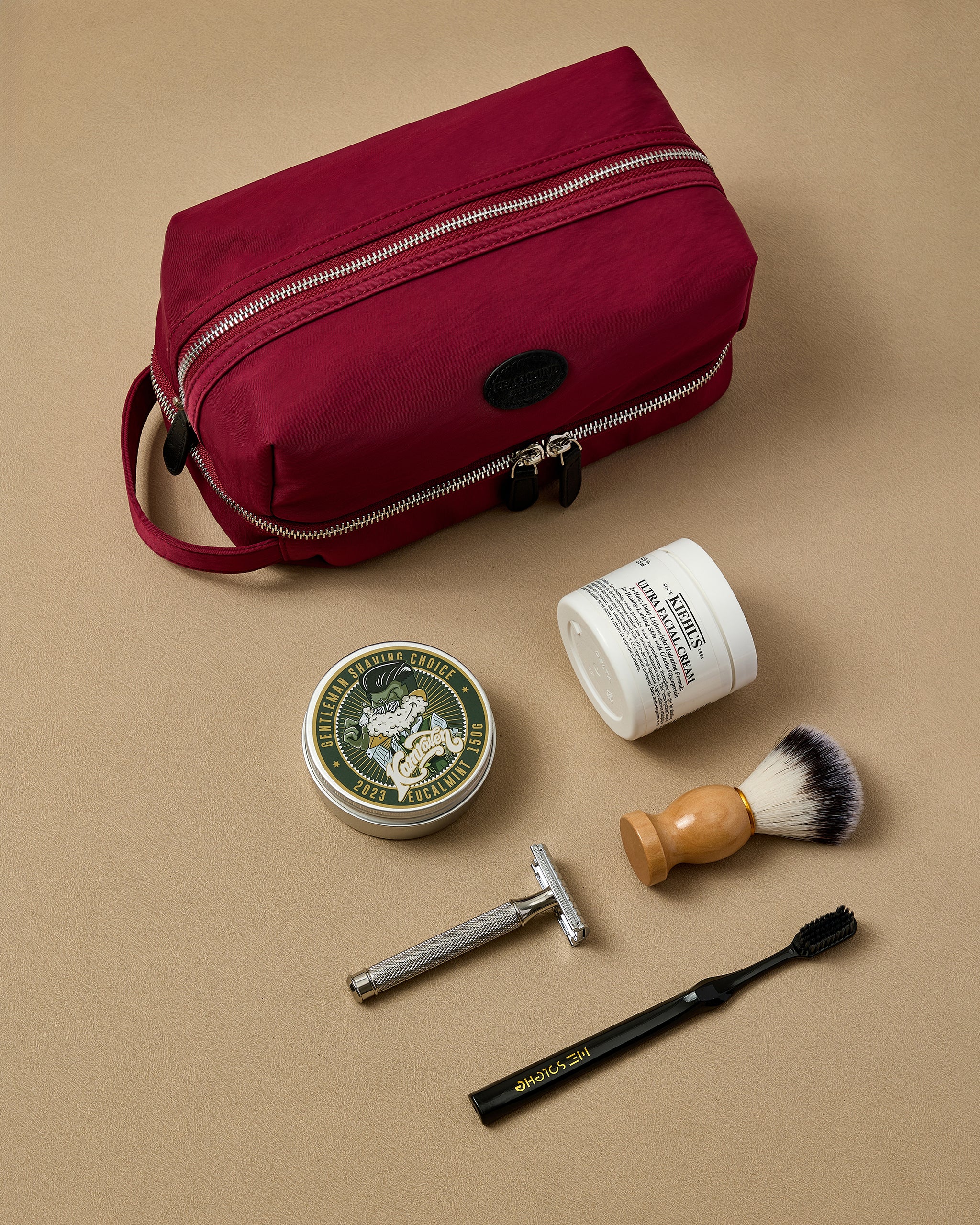 Red toiletry bag with shaving products on a beige background