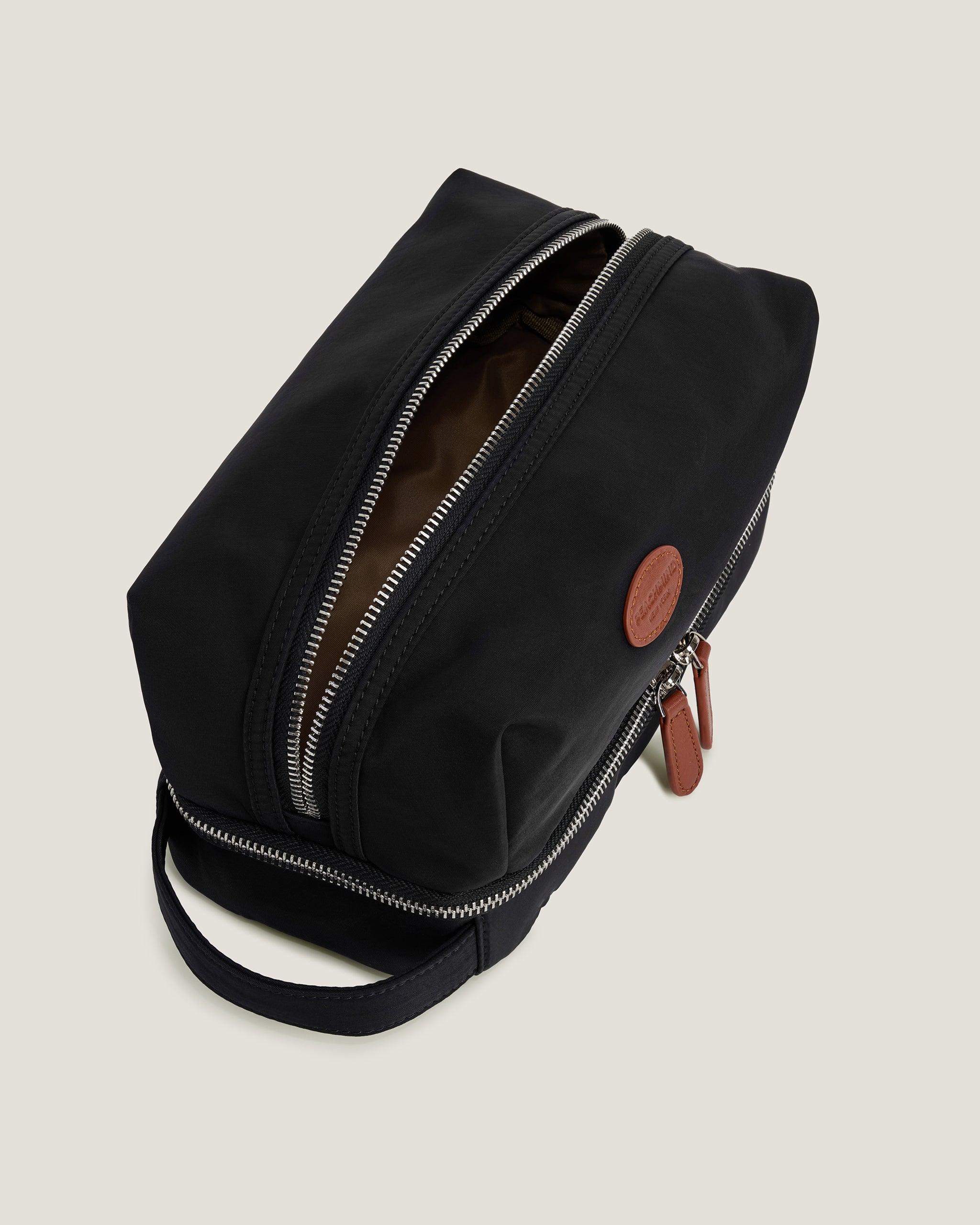 Black toiletry bag with open zipper on a light gray background