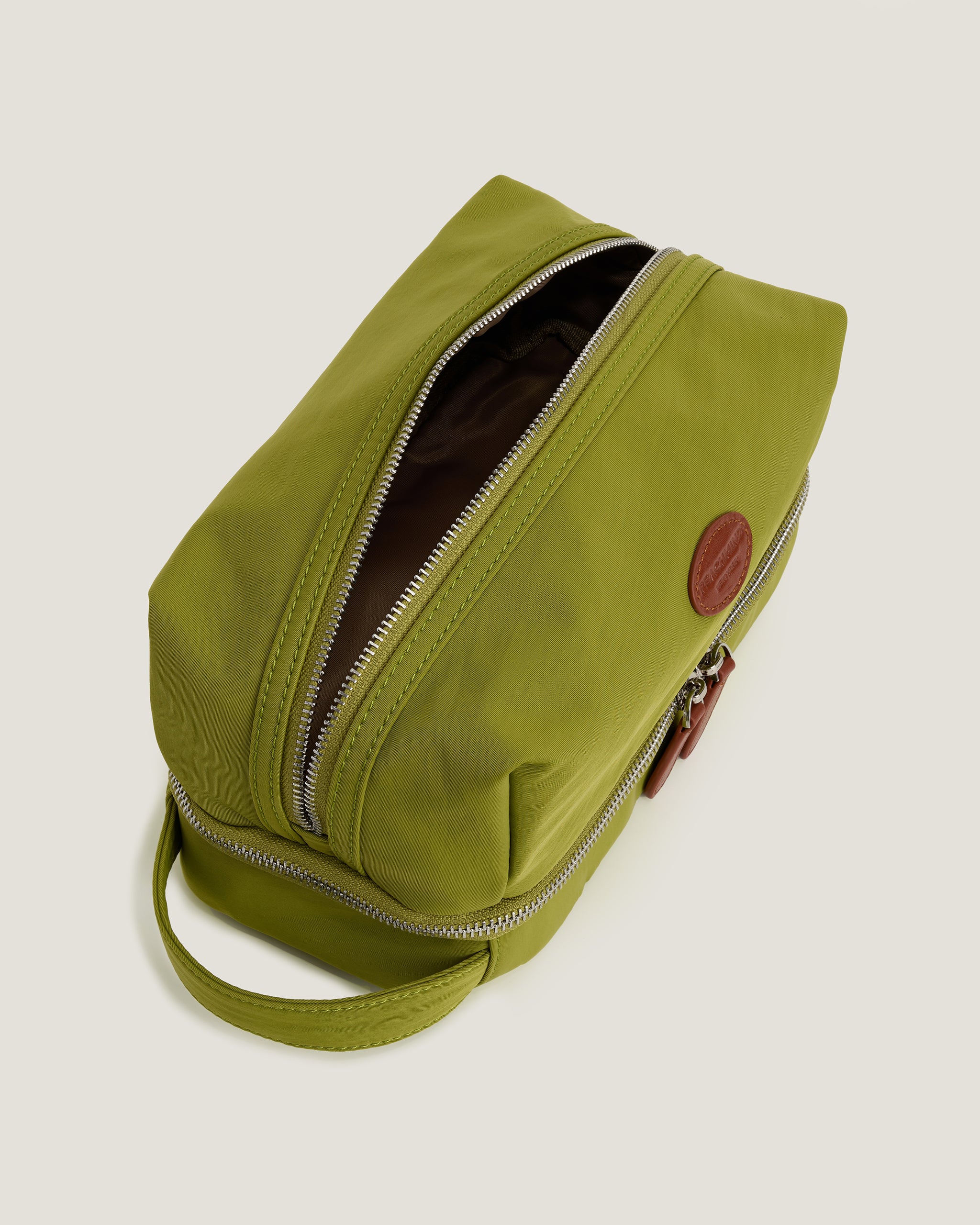 Green toiletry bag with a zipper on a light beige background