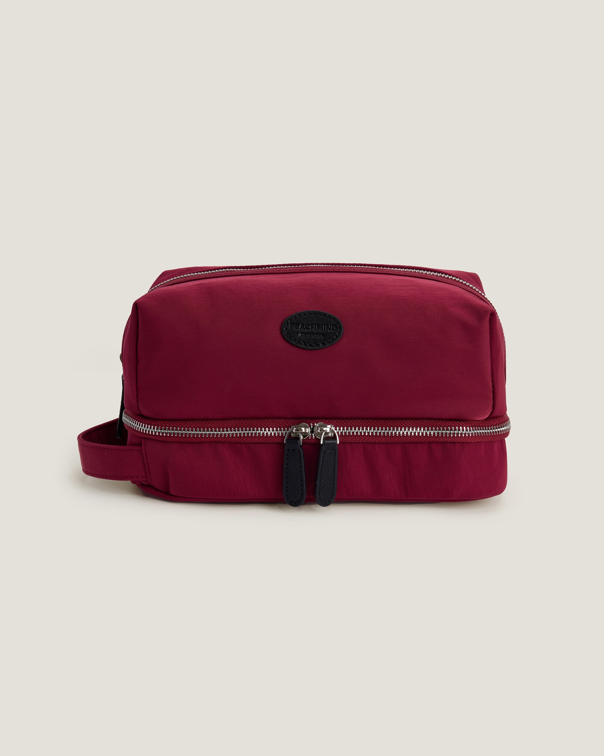 Red toiletry bag with a visible brand logo on a beige background
