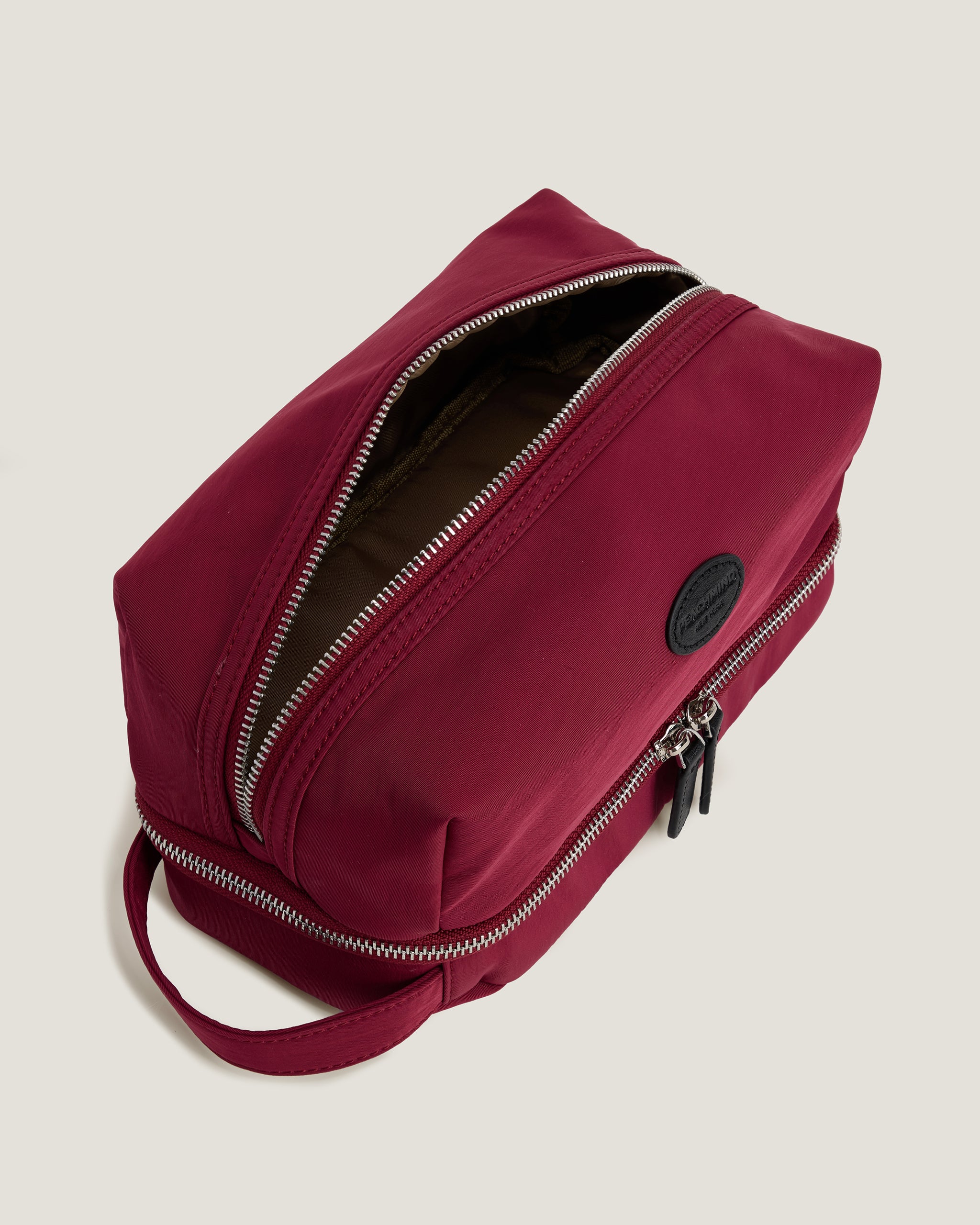 Red toiletry bag with a black patch on a beige background