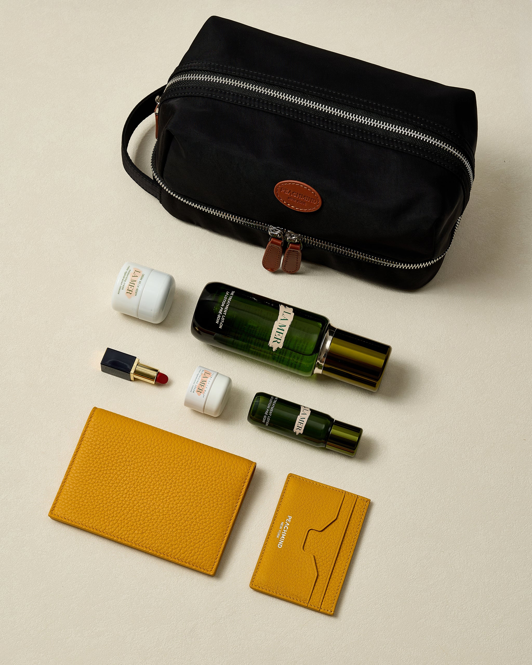 Black toiletry bag with cosmetic items on a beige background