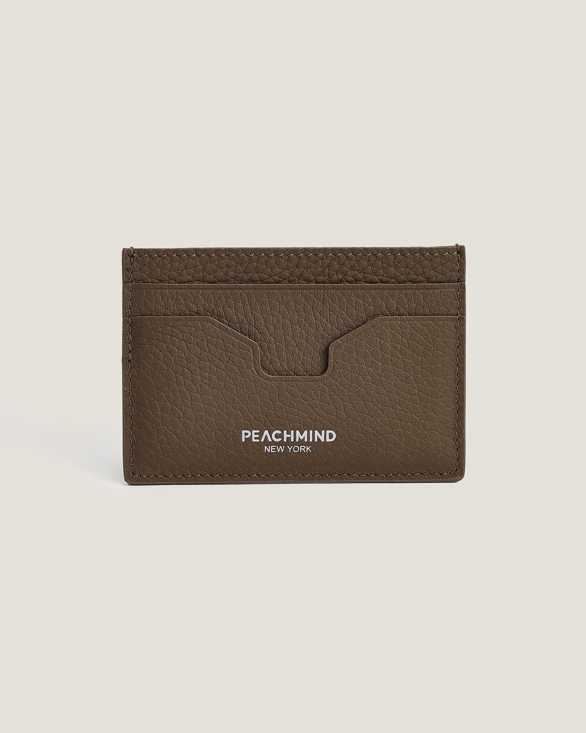 Brown leather cardholder with 'Peachmind New York' branding on a beige background