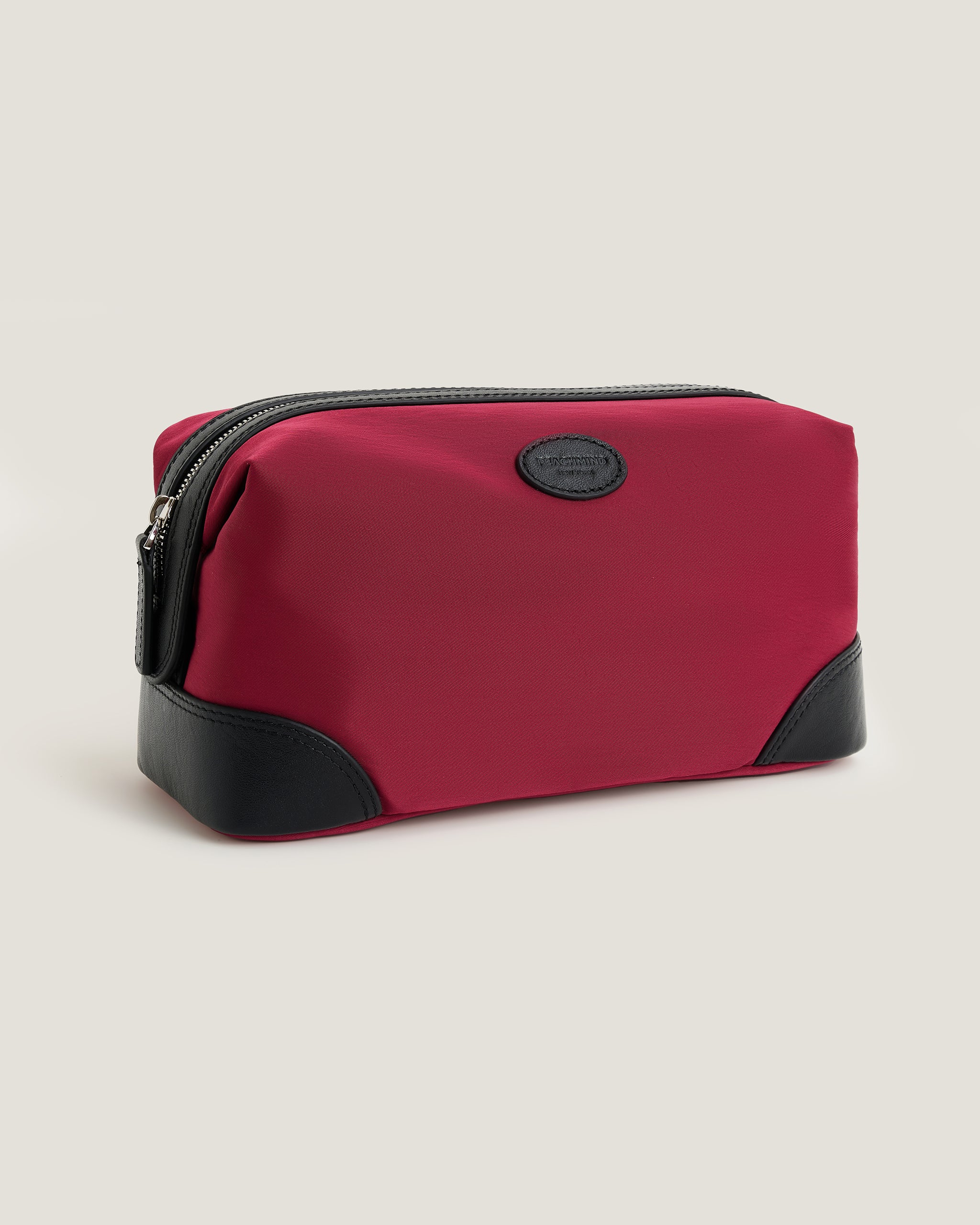 Red toiletry bag with black accents on a beige background