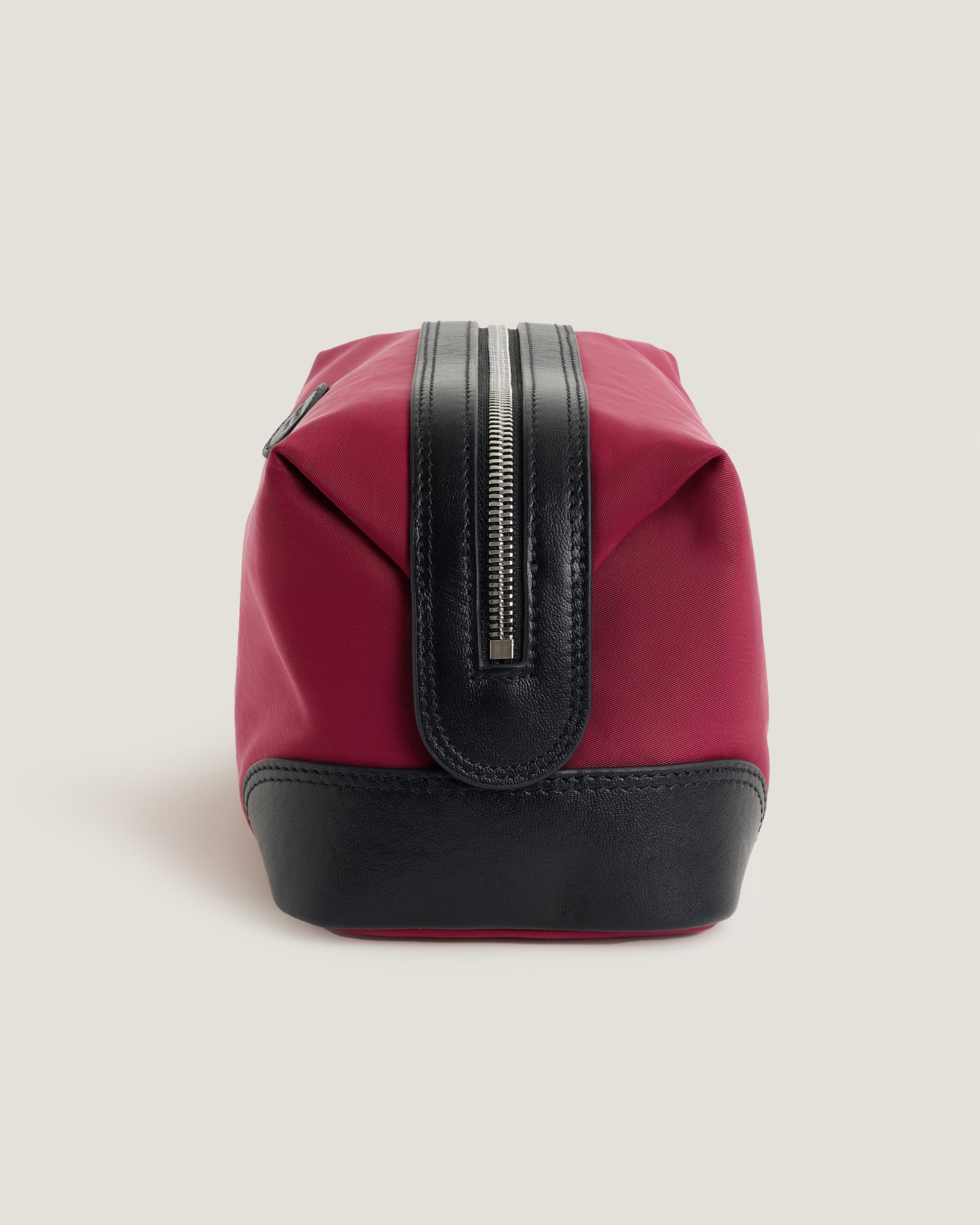 Red toiletry bag with black accents on a light gray background