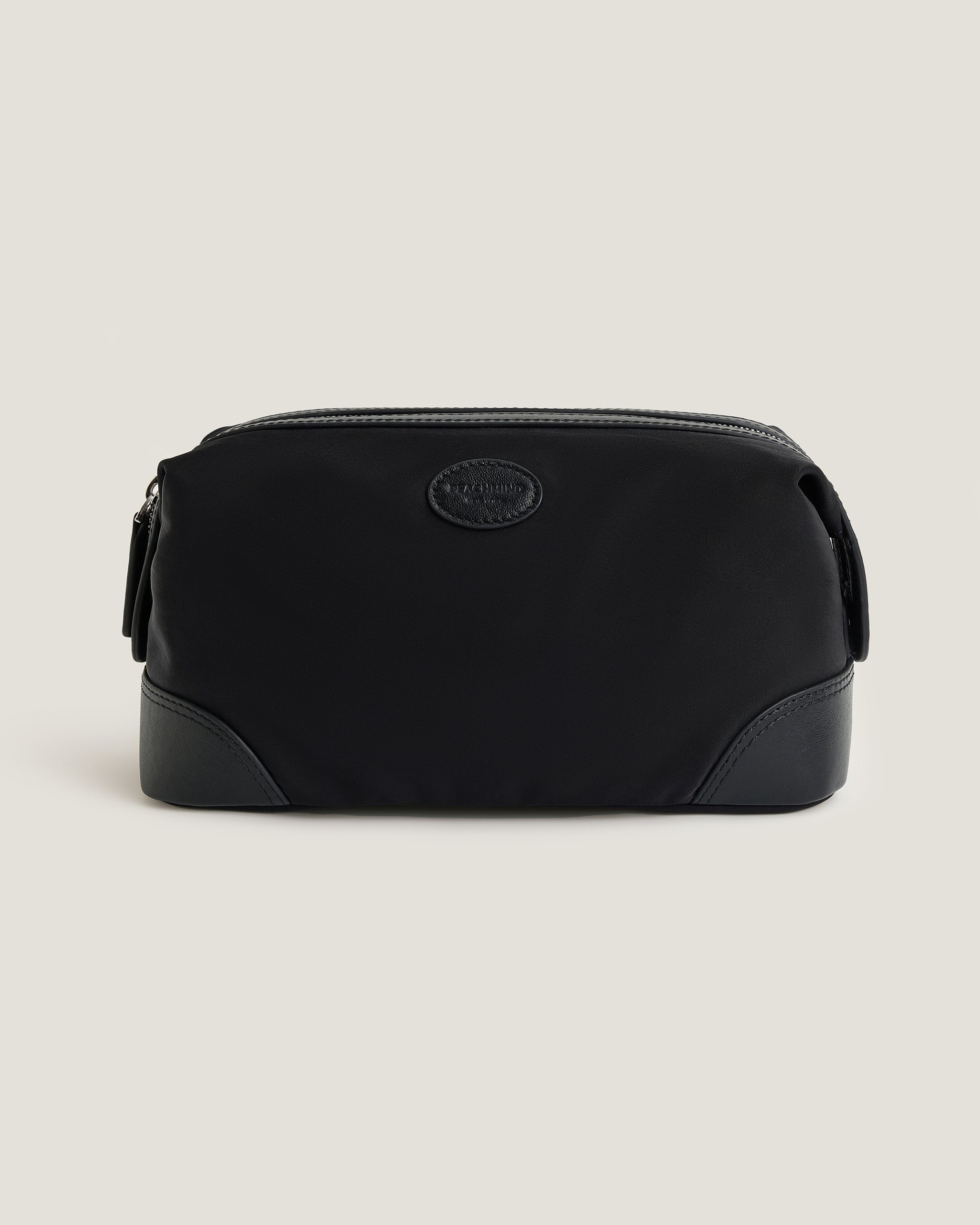 Black toiletry bag with a visible PEACHMIND logo on a beige background