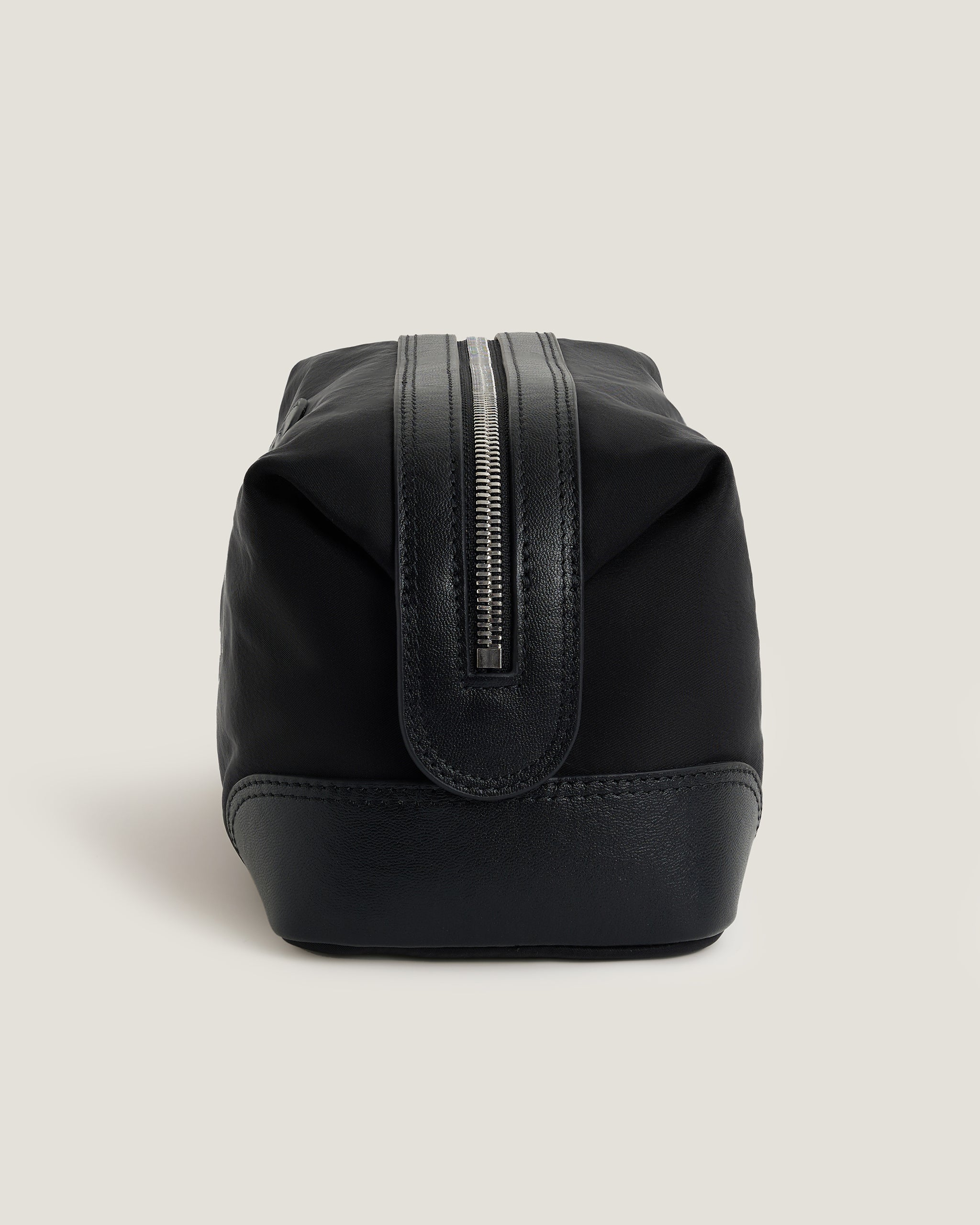 Black toiletry bag with a zipper on a light gray background