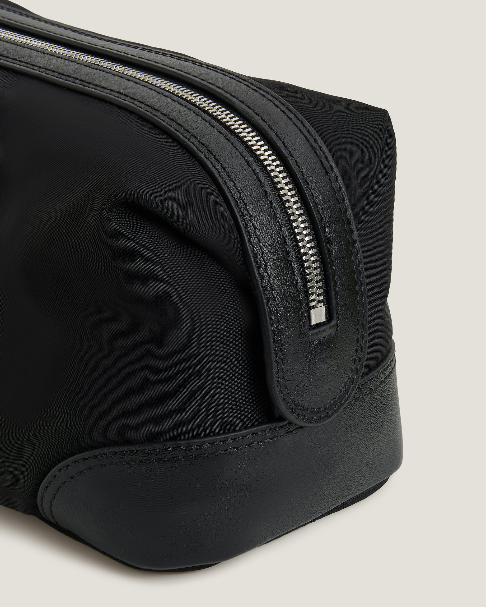 Black toiletry bag with a zipper on a light gray background