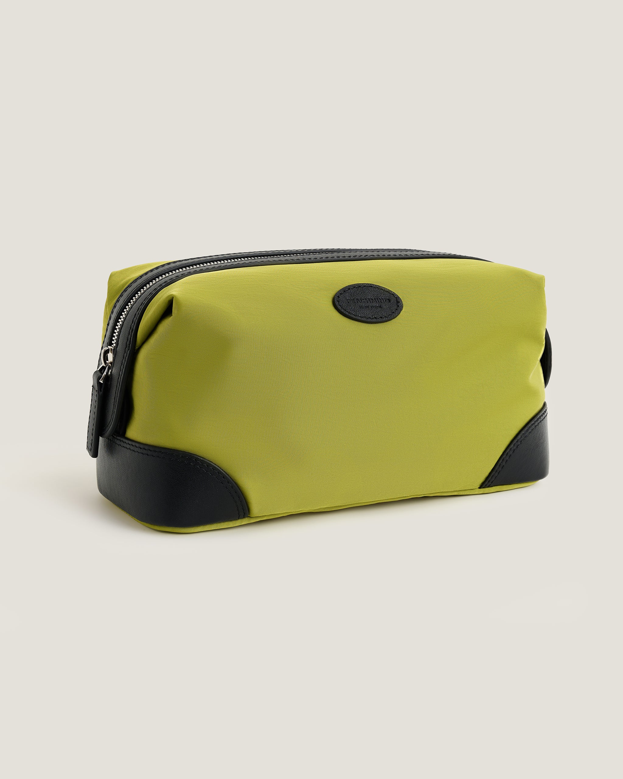 Green toiletry bag with black accents on a beige background