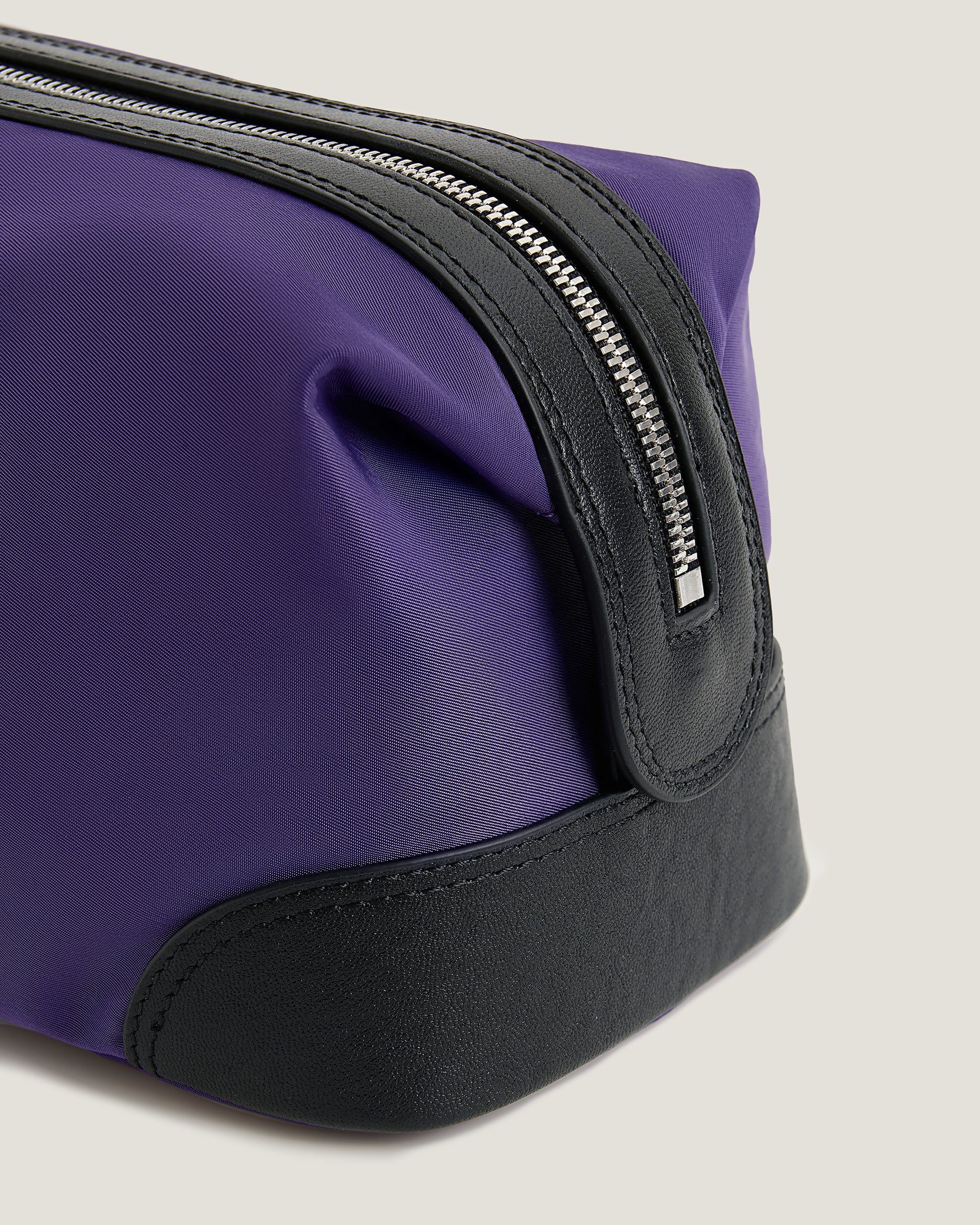 Green toiletry bag with black zipper on a light beige background