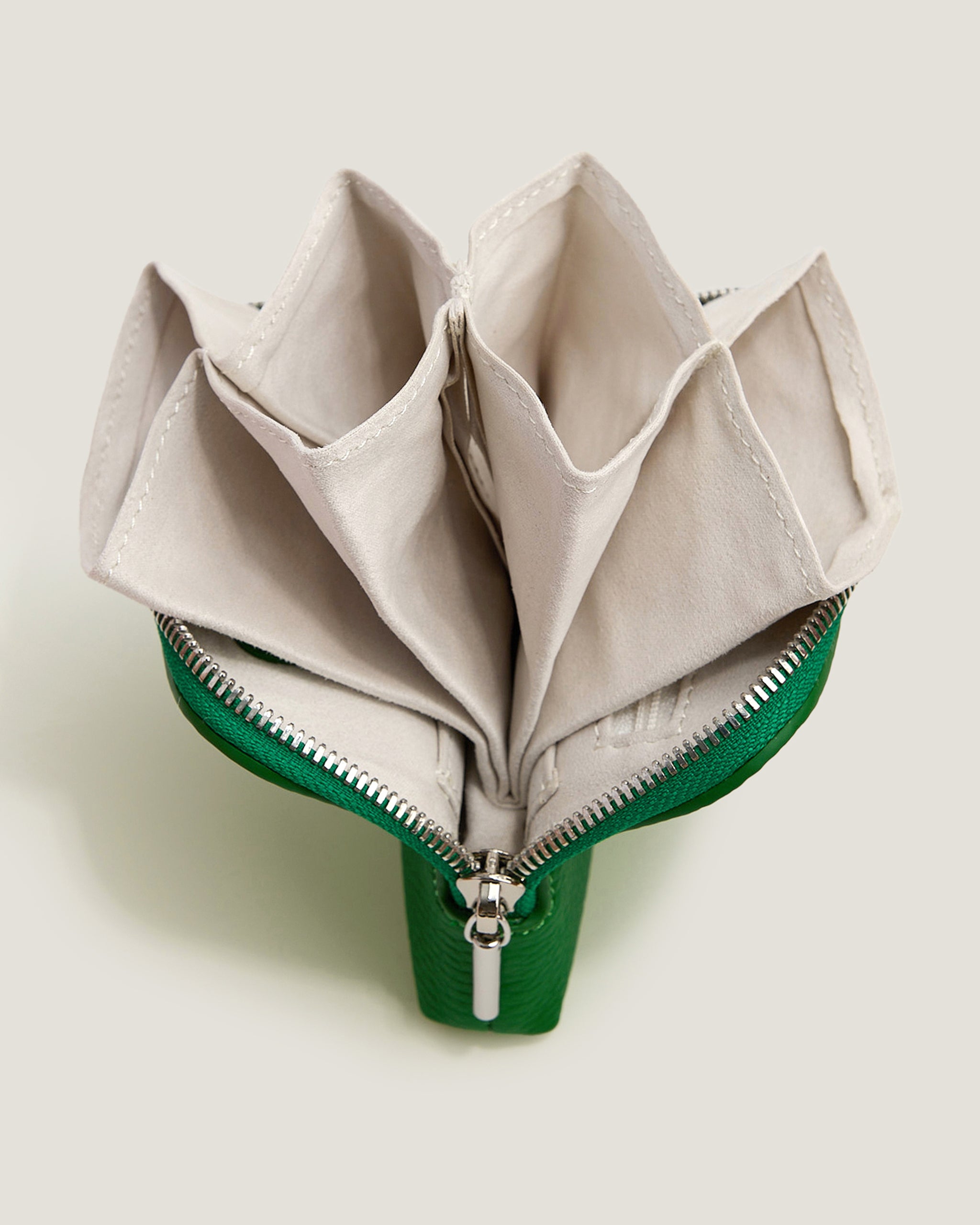 Green zipper pouch with beige interior on a light background
