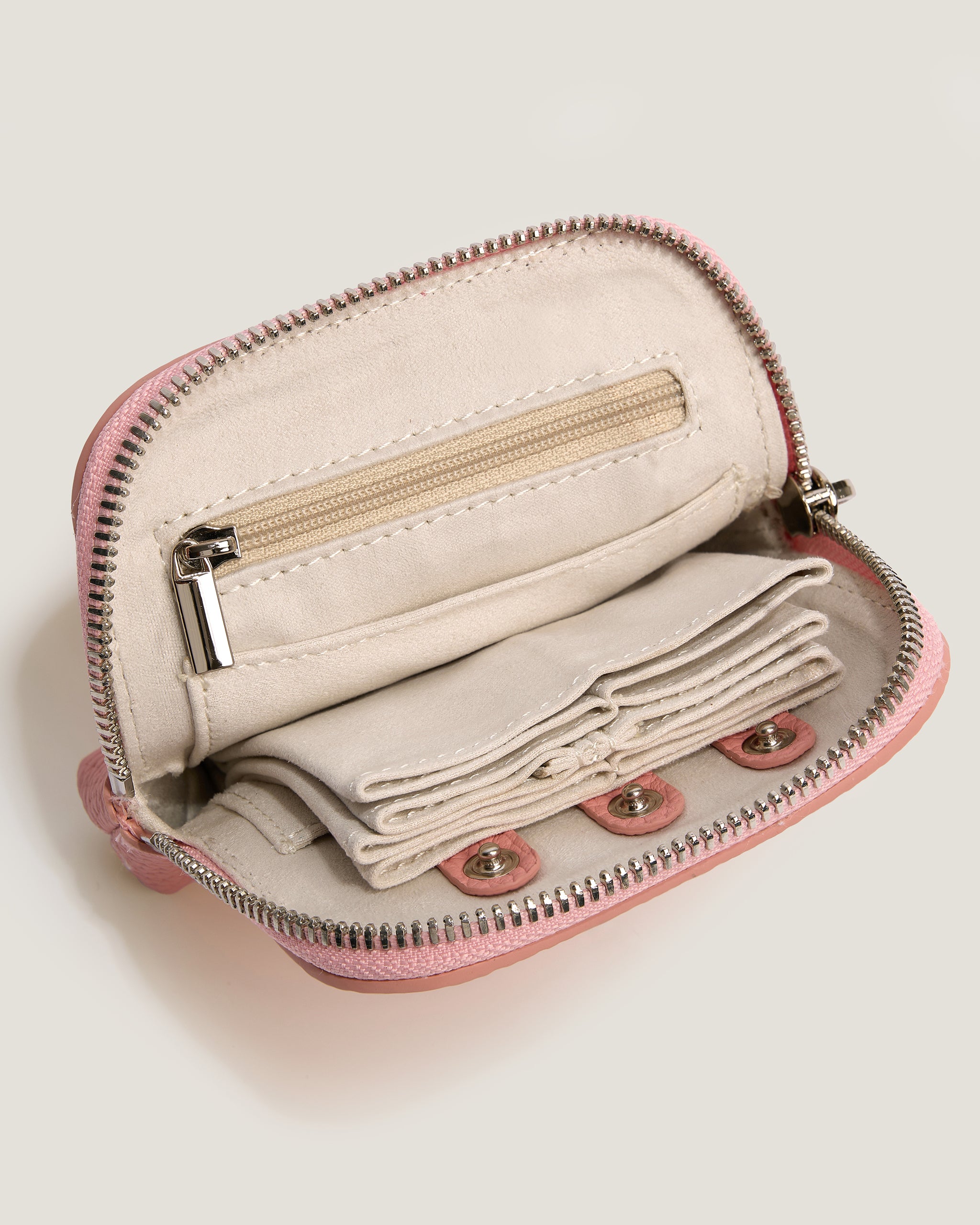Small pink zippered pouch with beige interior on a light gray background