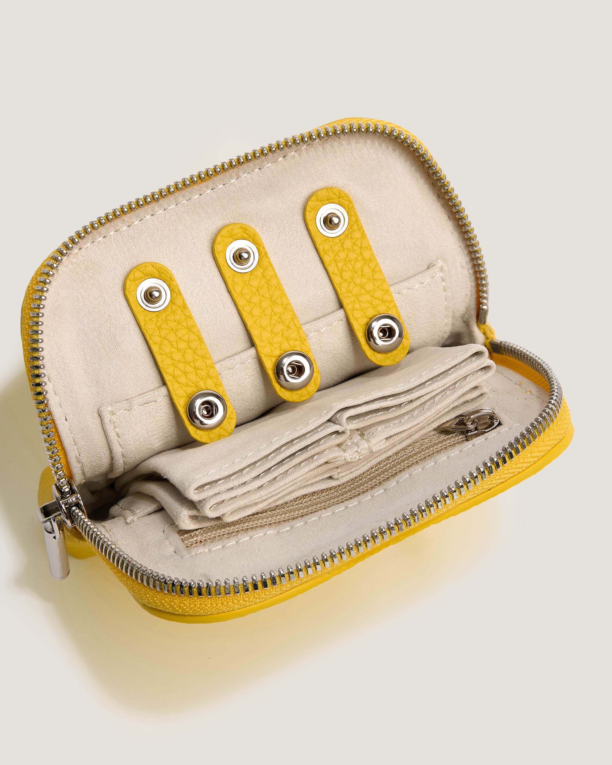 Small beige pouch with yellow accents and zippers on a light gray background