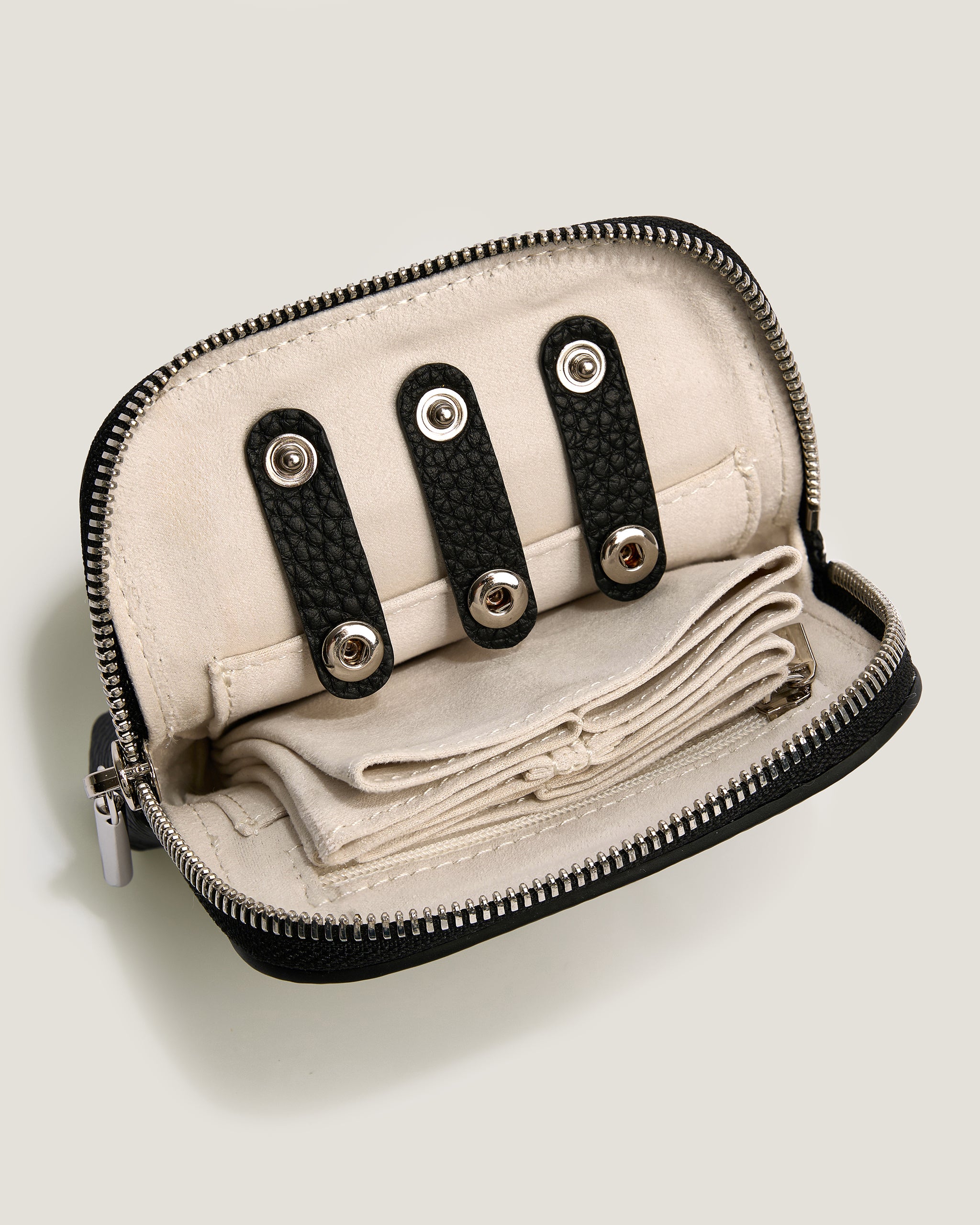 Small beige pouch with black zipper and decorative straps on a light gray background