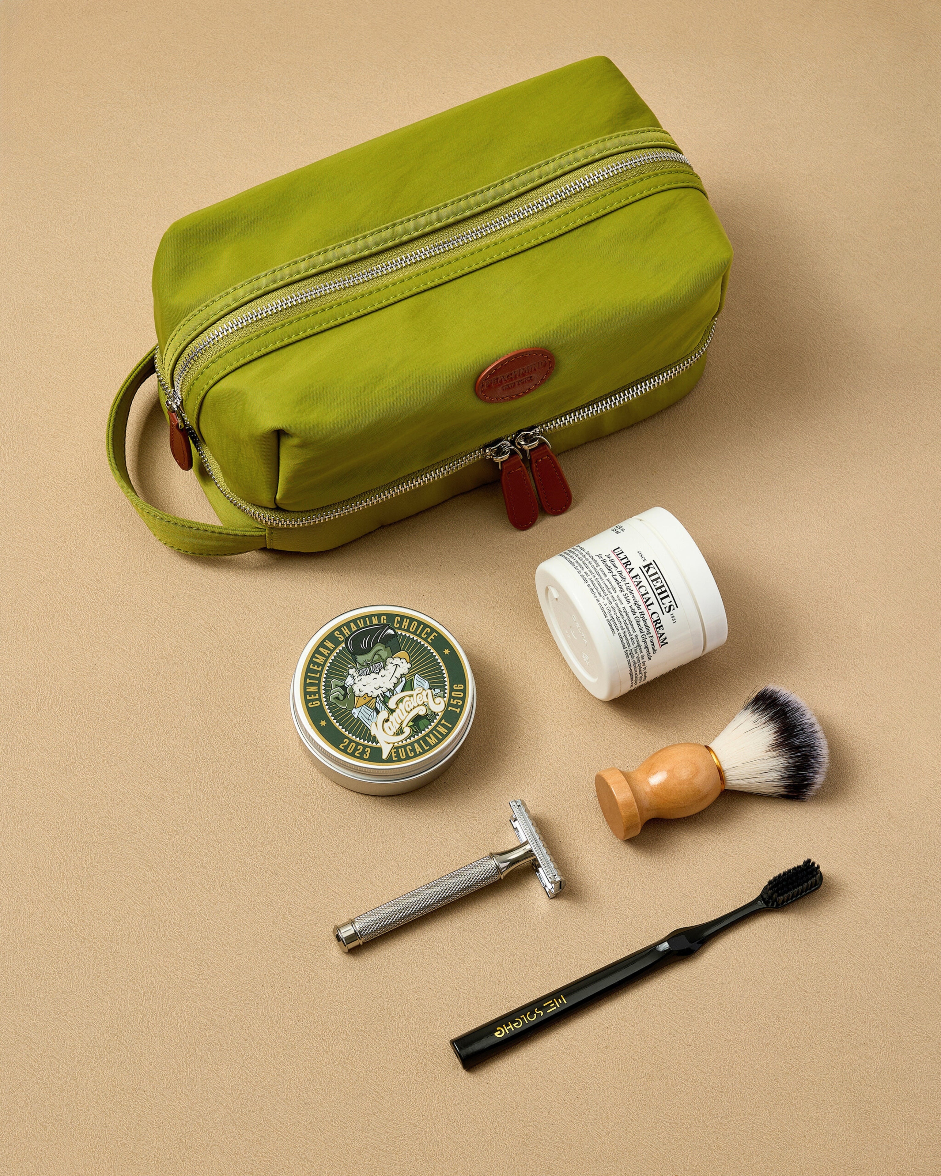 Green toiletry bag with shaving products on a beige background
