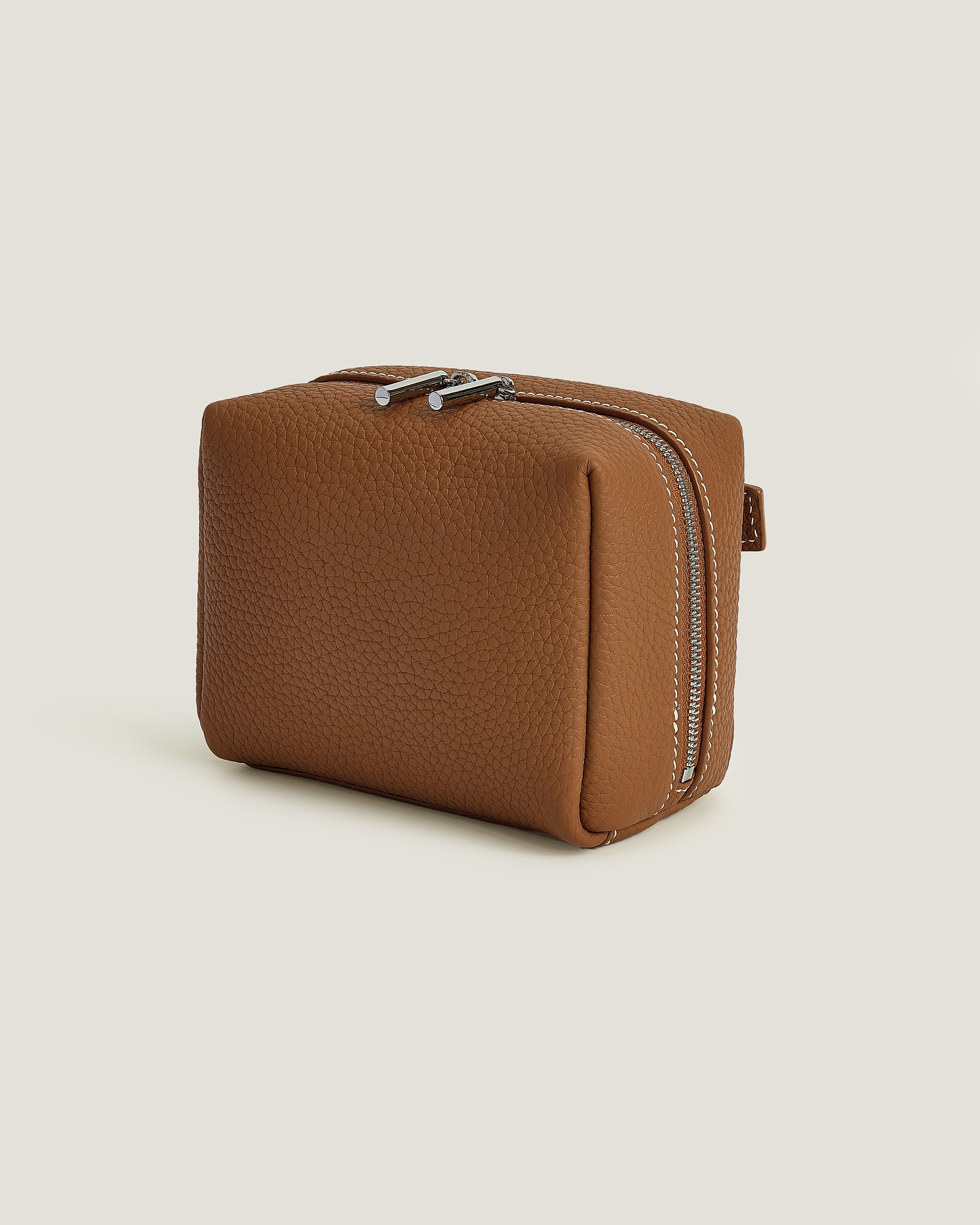 Brown textured makeup pouch with a zipper on a beige background