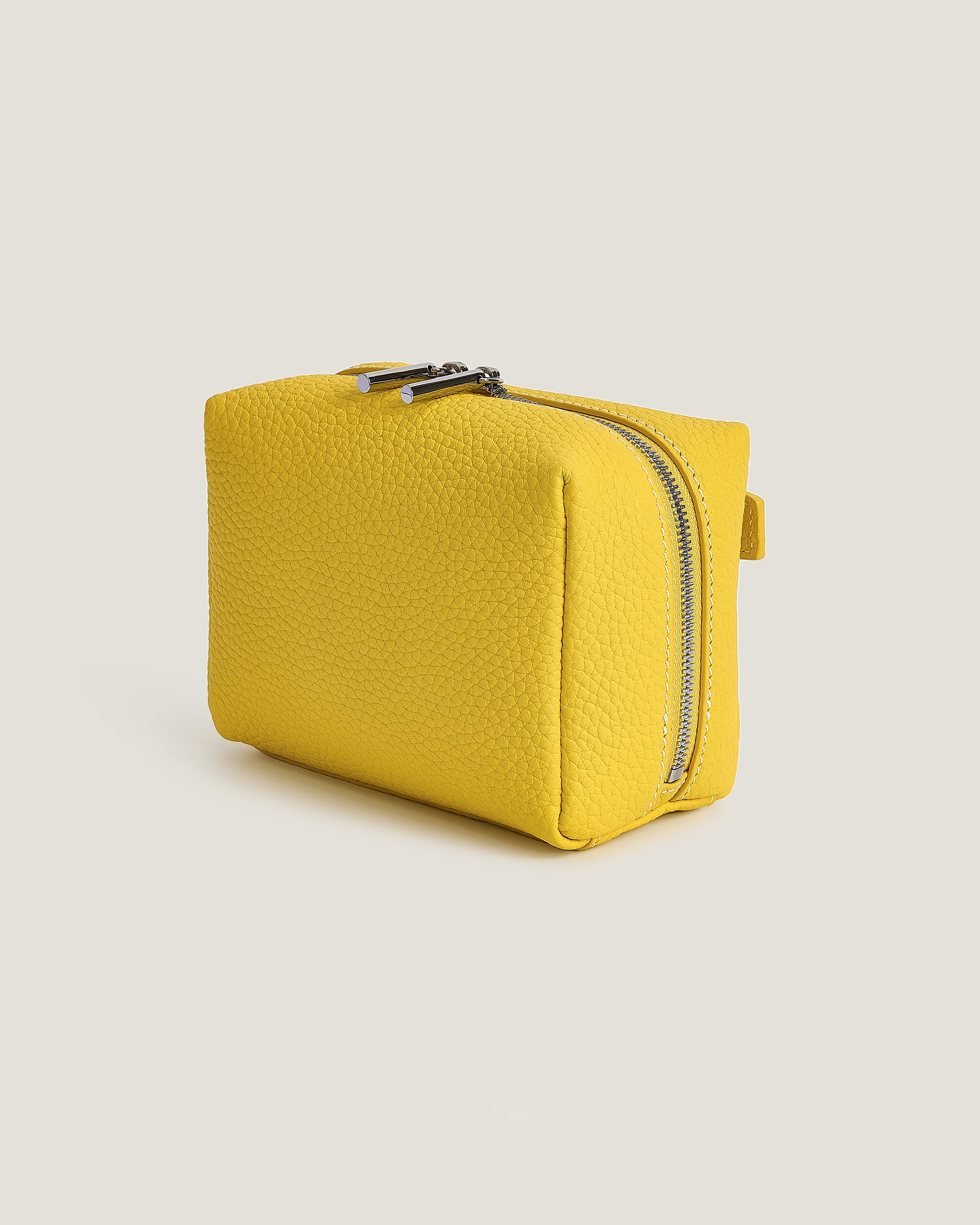 Yellow mini makup pouch with a zipper on a beige background