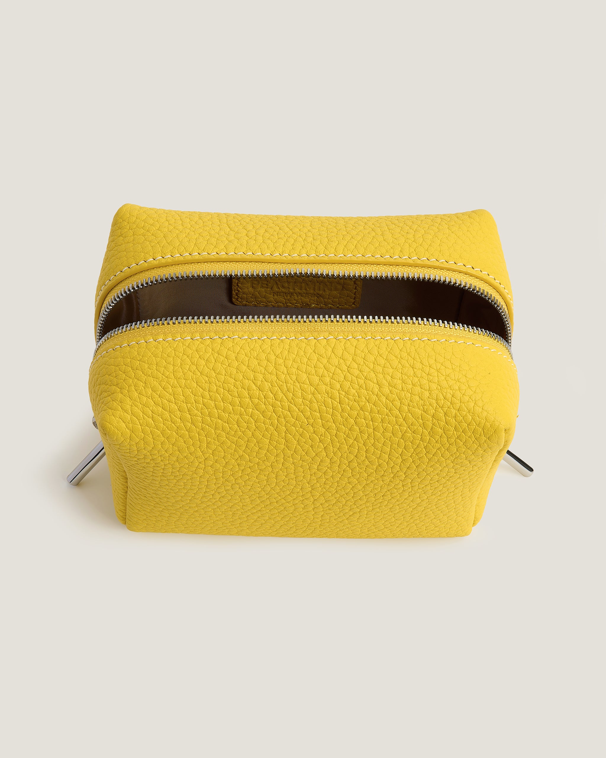 Yellow mini makeup pouch with a zipper on a light beige background