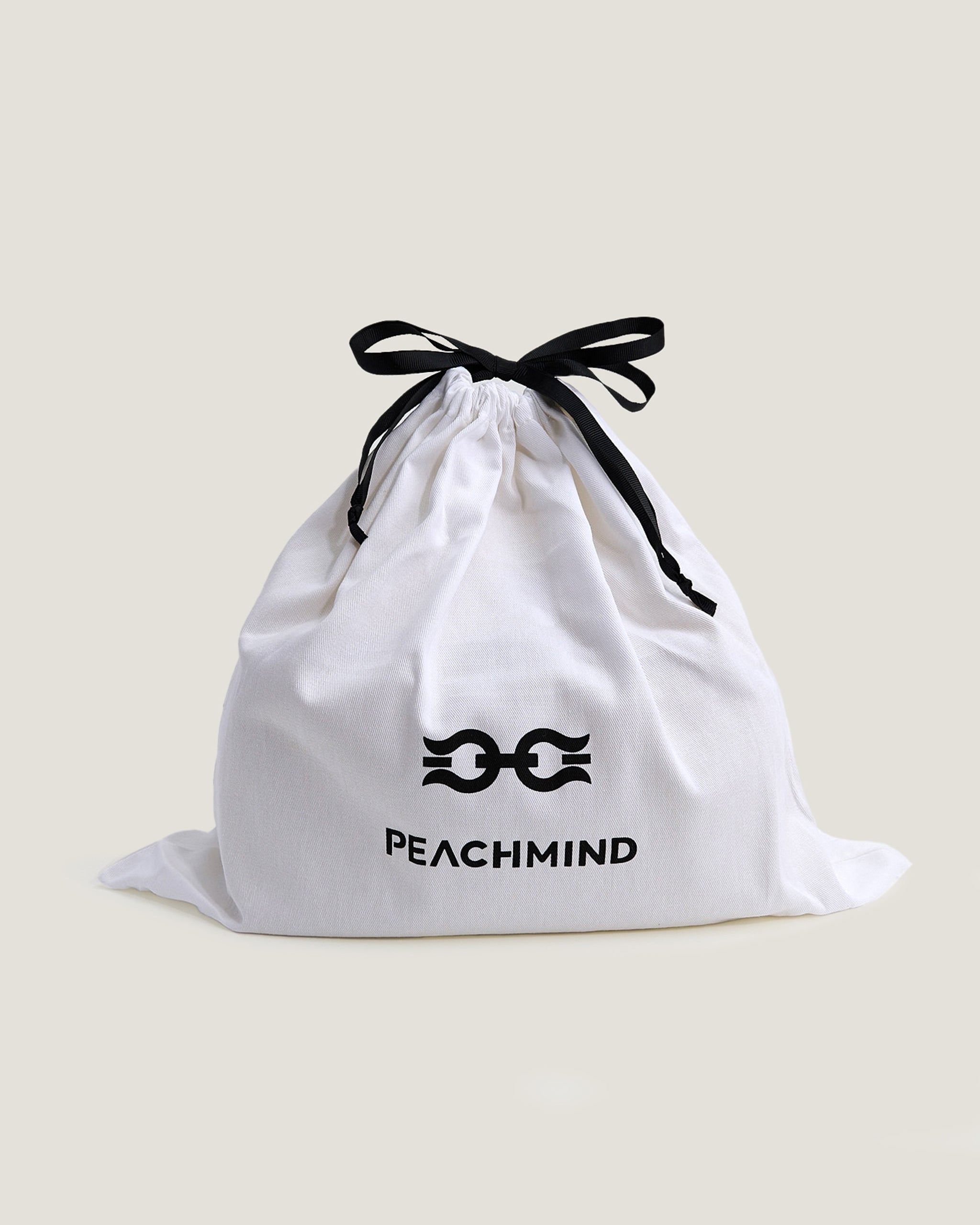 White drawstring bag with black logo and text on a beige background