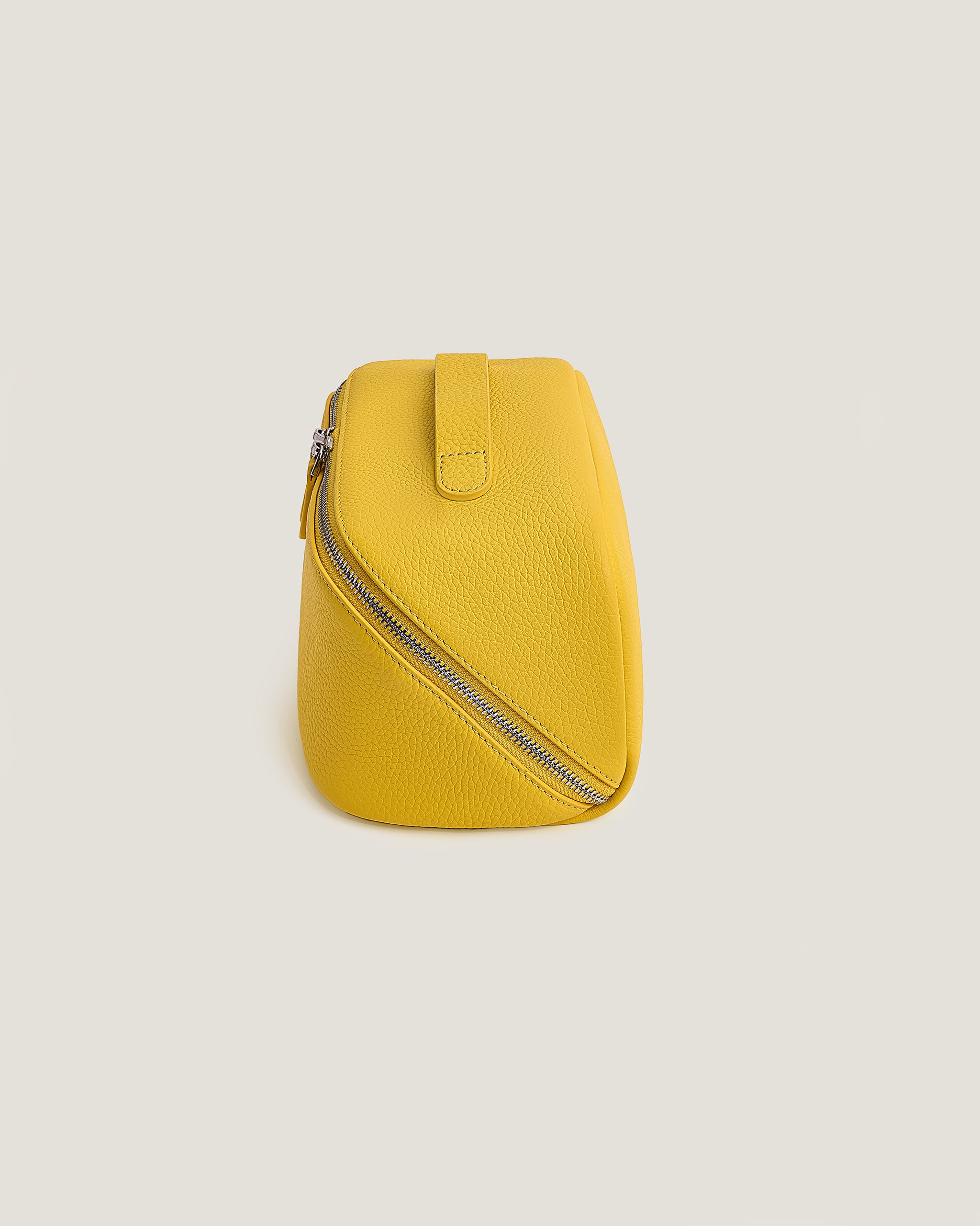Yellow leather makeup bag with a zipper on a light beige background