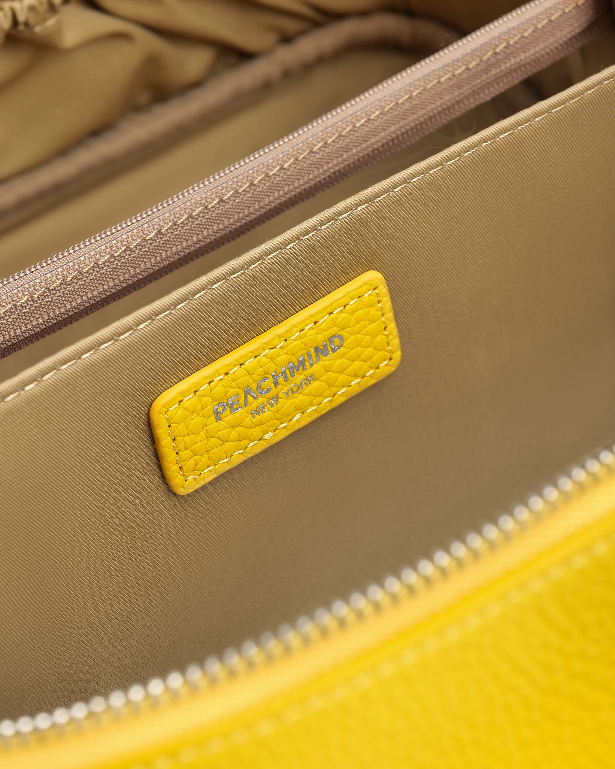 Close-up of a beige and yellow handbag with a visible 'PEACHMIND' brand label.