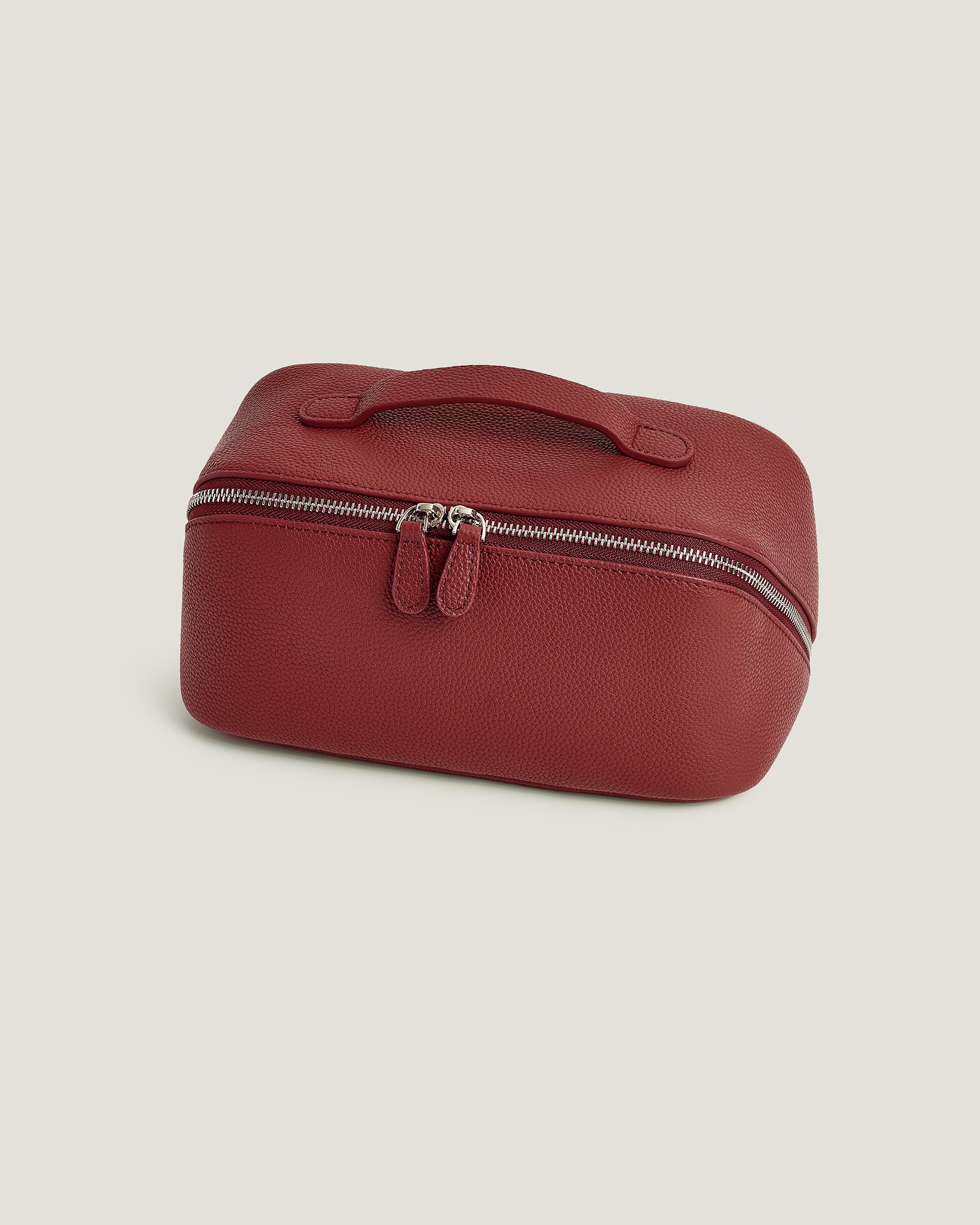 Red makeup bag with a zipper on a beige background